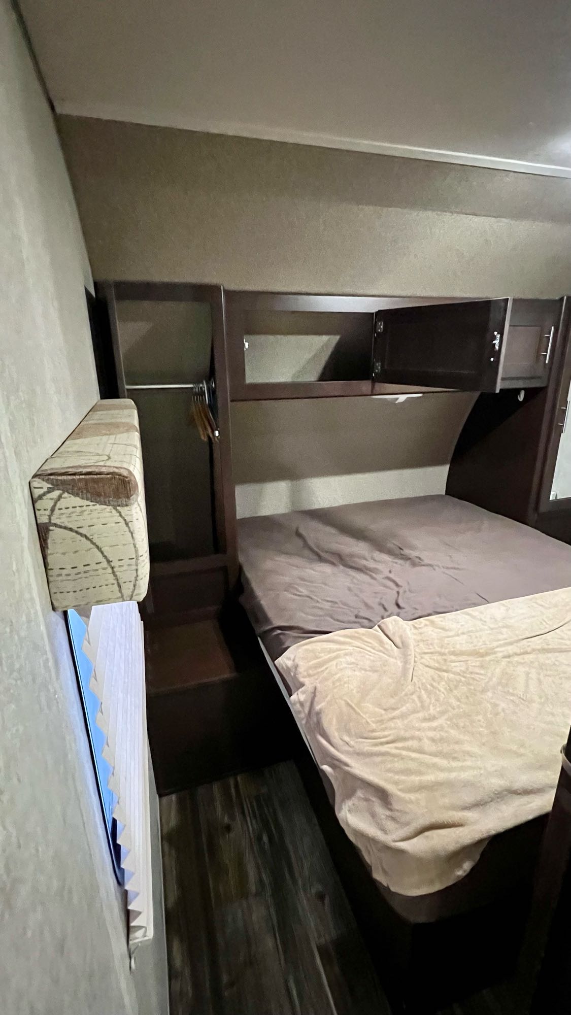 Cozy RV rental bedroom: Features a comfortable bed, overhead cabinets, and a compact wardrobe, perfect for mobile travel accommodations.. Forest River Cherokee 2015