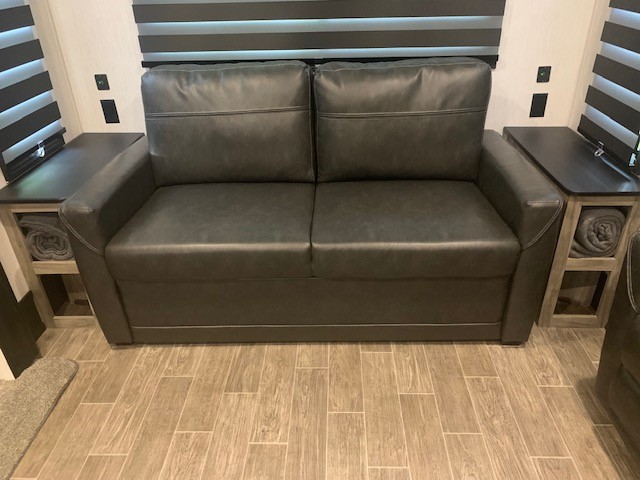 Comfortable dark grey sofa with built-in side tables & storage in an RV rental. Perfect for relaxing.. Forest River Cherokee Arctic Wolf 2022