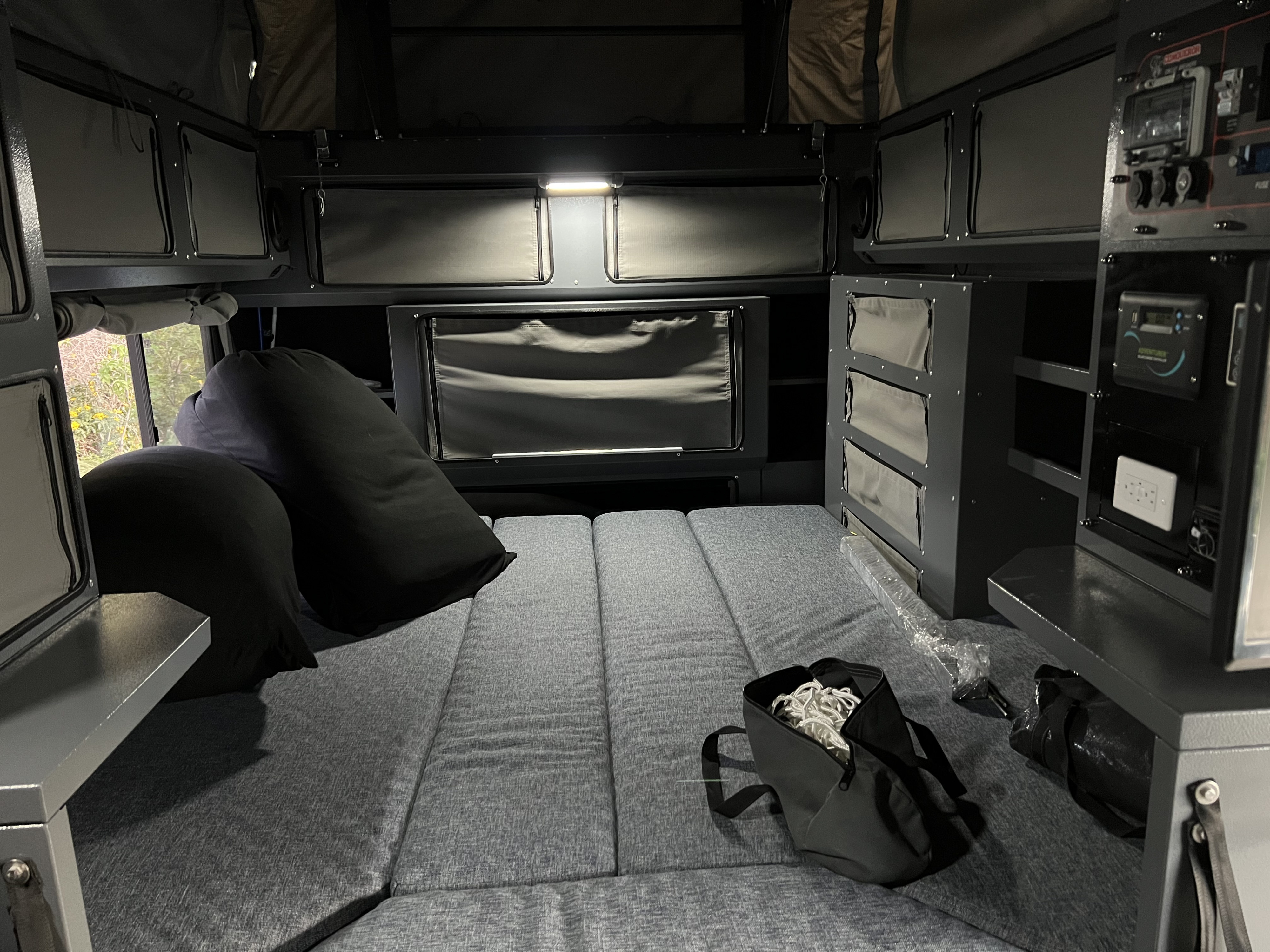 Functional RV rental interior: grey sleeping area, integrated storage, and control panel for an organized adventure setup.. Conqueror UEV490 2022