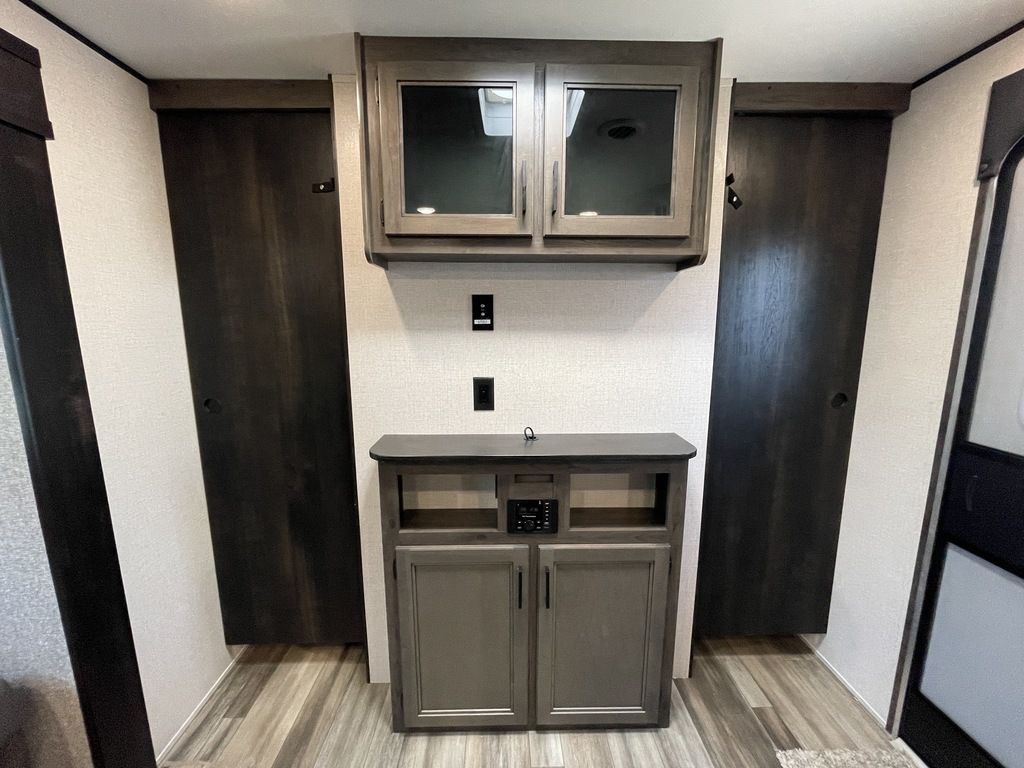 This RV rental interior features modern wood cabinetry, dual dark doors, and an entertainment center with ample storage.. Highland Ridge open range 2022