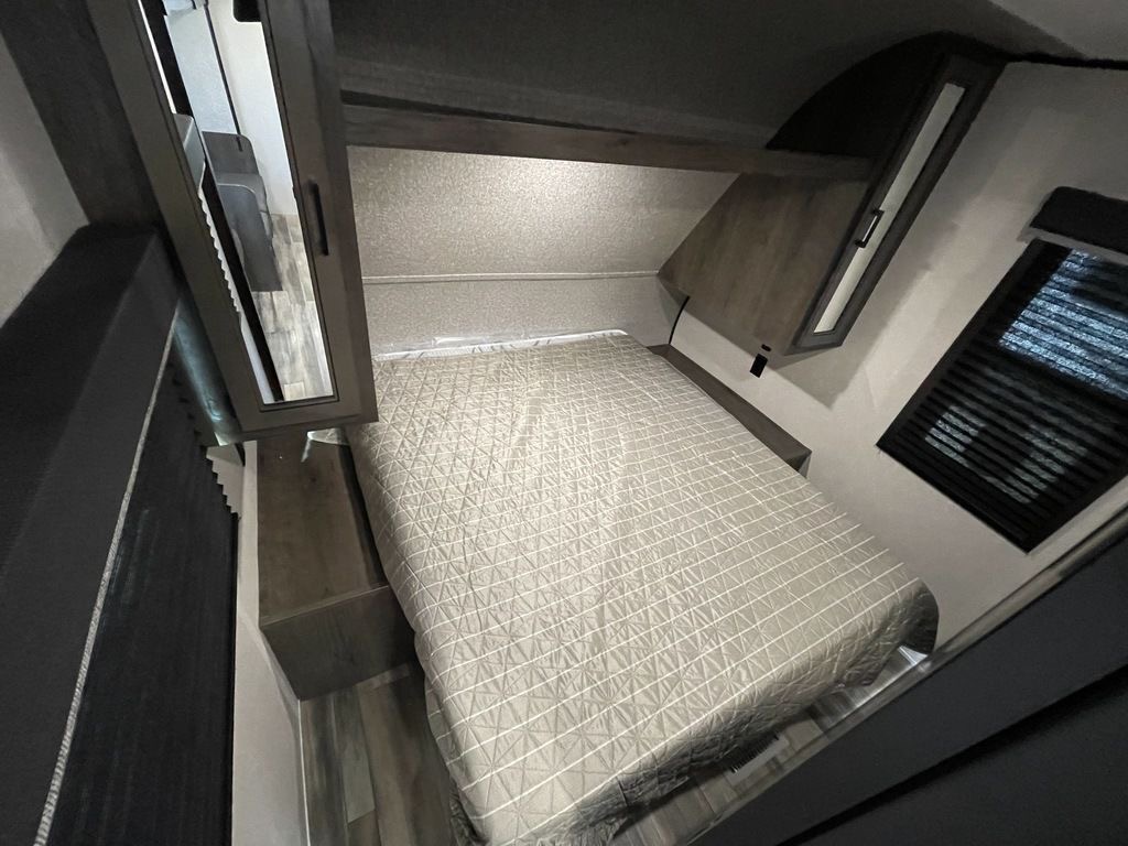 Cozy RV rental bedroom featuring a comfortable bed, ample overhead storage, and a window for natural light.. Highland Ridge open range 2022