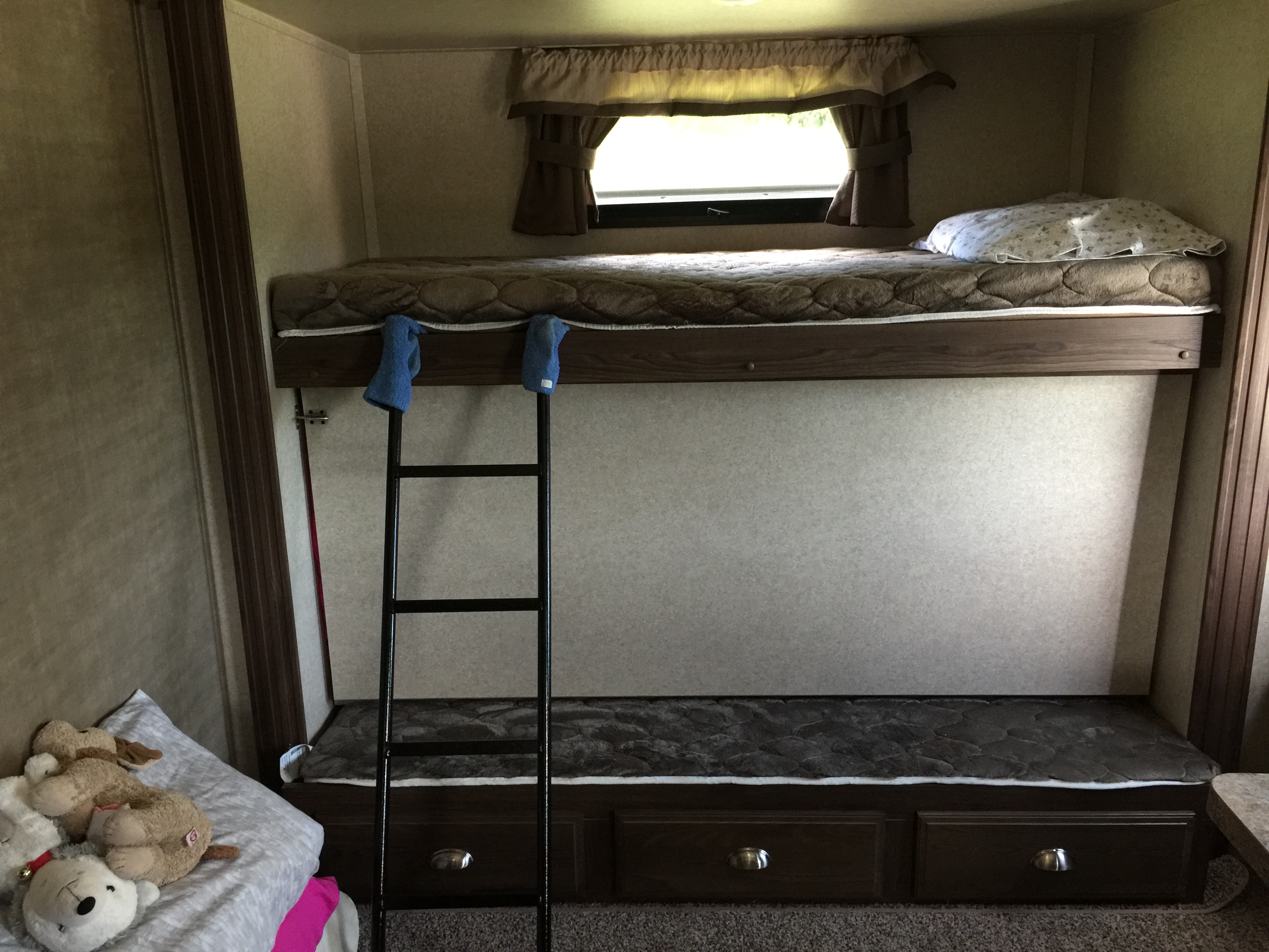 RV rental bunk beds: a cozy sleeping area inside a camper with a ladder, window, and storage drawers.. Forest River Flagstaff Classic Super Lite 2018