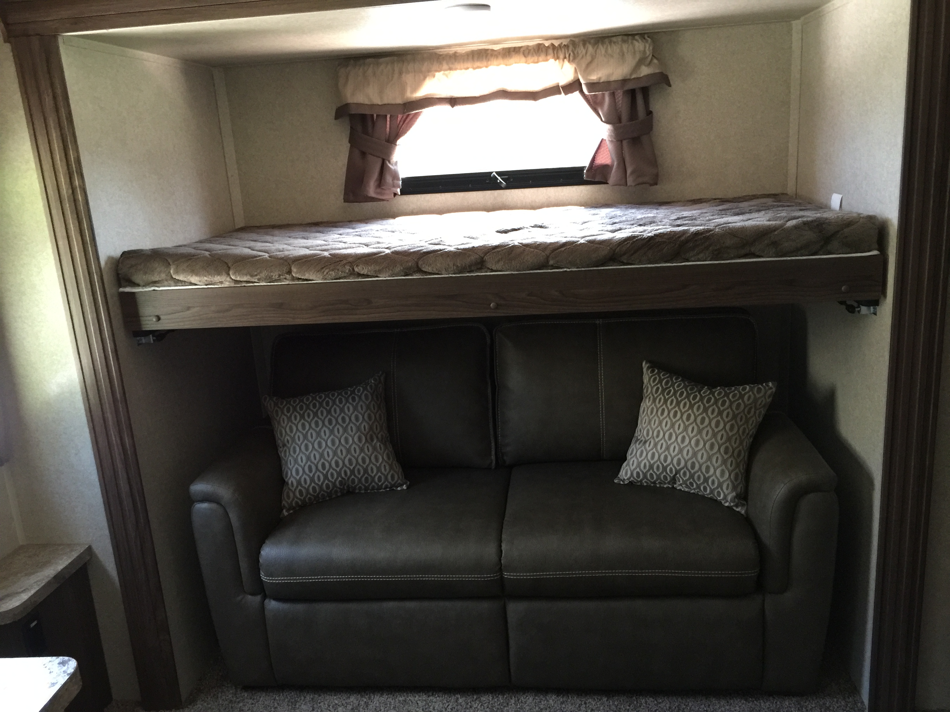 Comfortable RV rental interior: bunk bed over a cozy sofa with decorative pillows, perfect for family adventures.. Forest River Flagstaff Classic Super Lite 2018