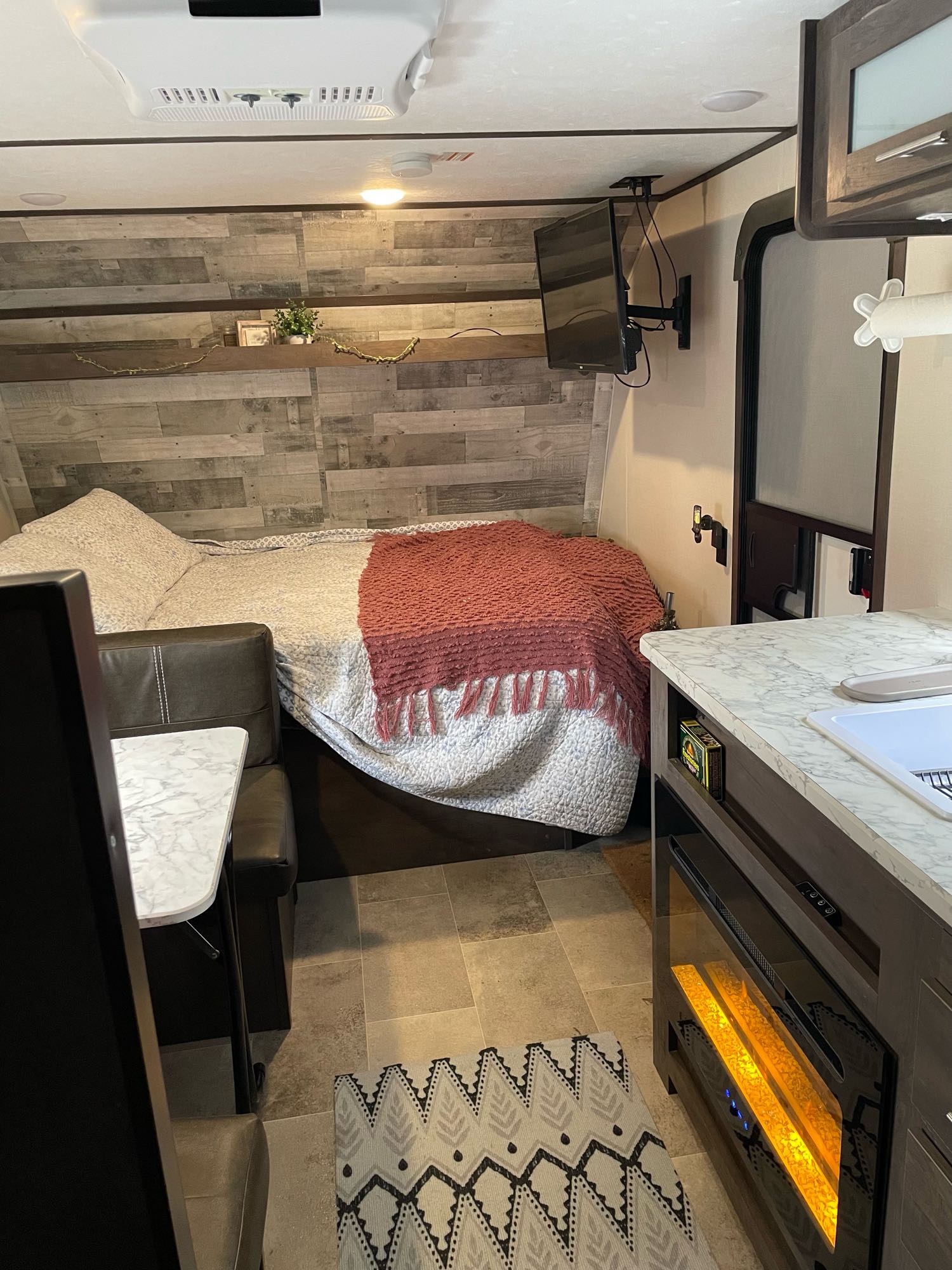 Experience comfort in this RV rental! Features a cozy bed, dining area, kitchen counter, and electric fireplace.. Coleman Lantern 17B 2022