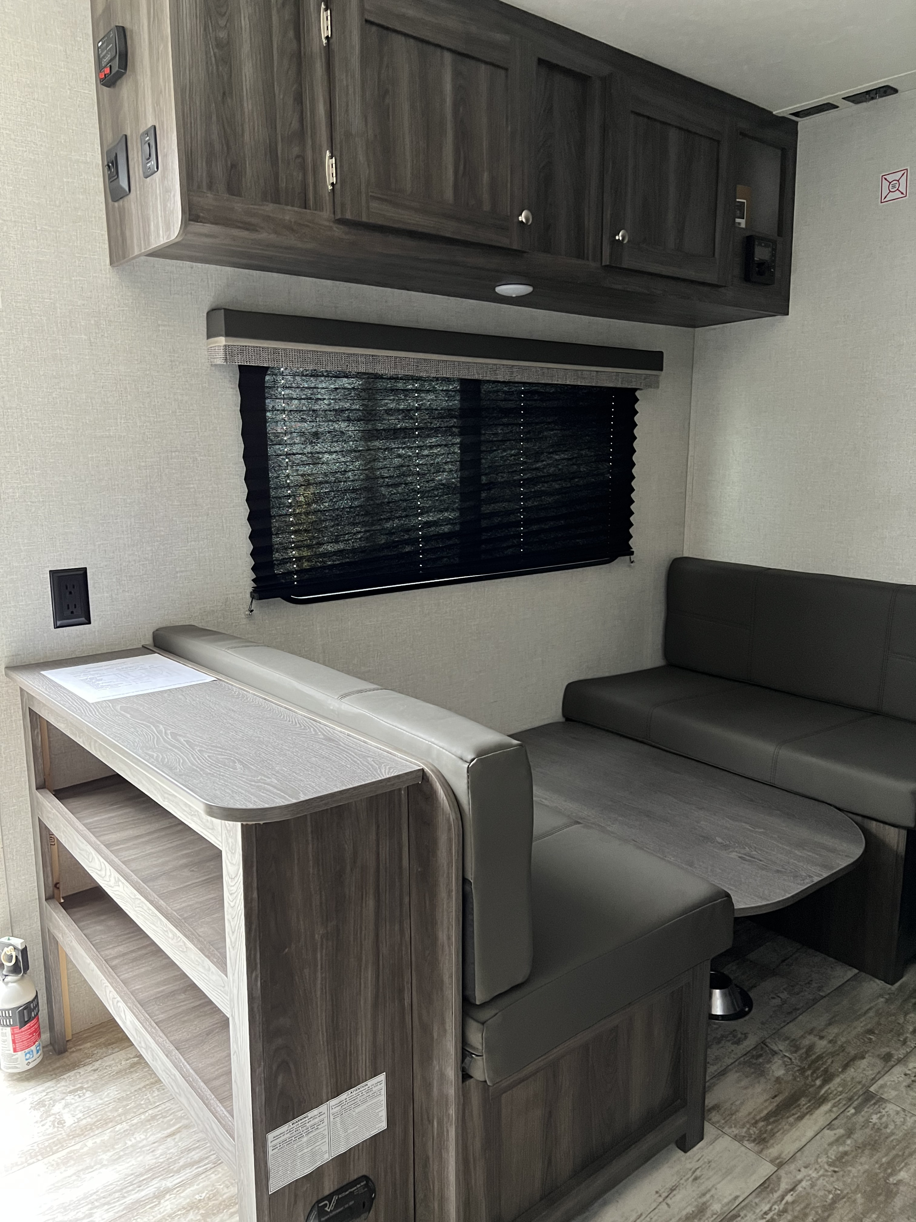 Inside an RV rental: a practical dinette with storage shelves, overhead cabinets, and window blinds.. Highland Ridge RV Open Range 2020