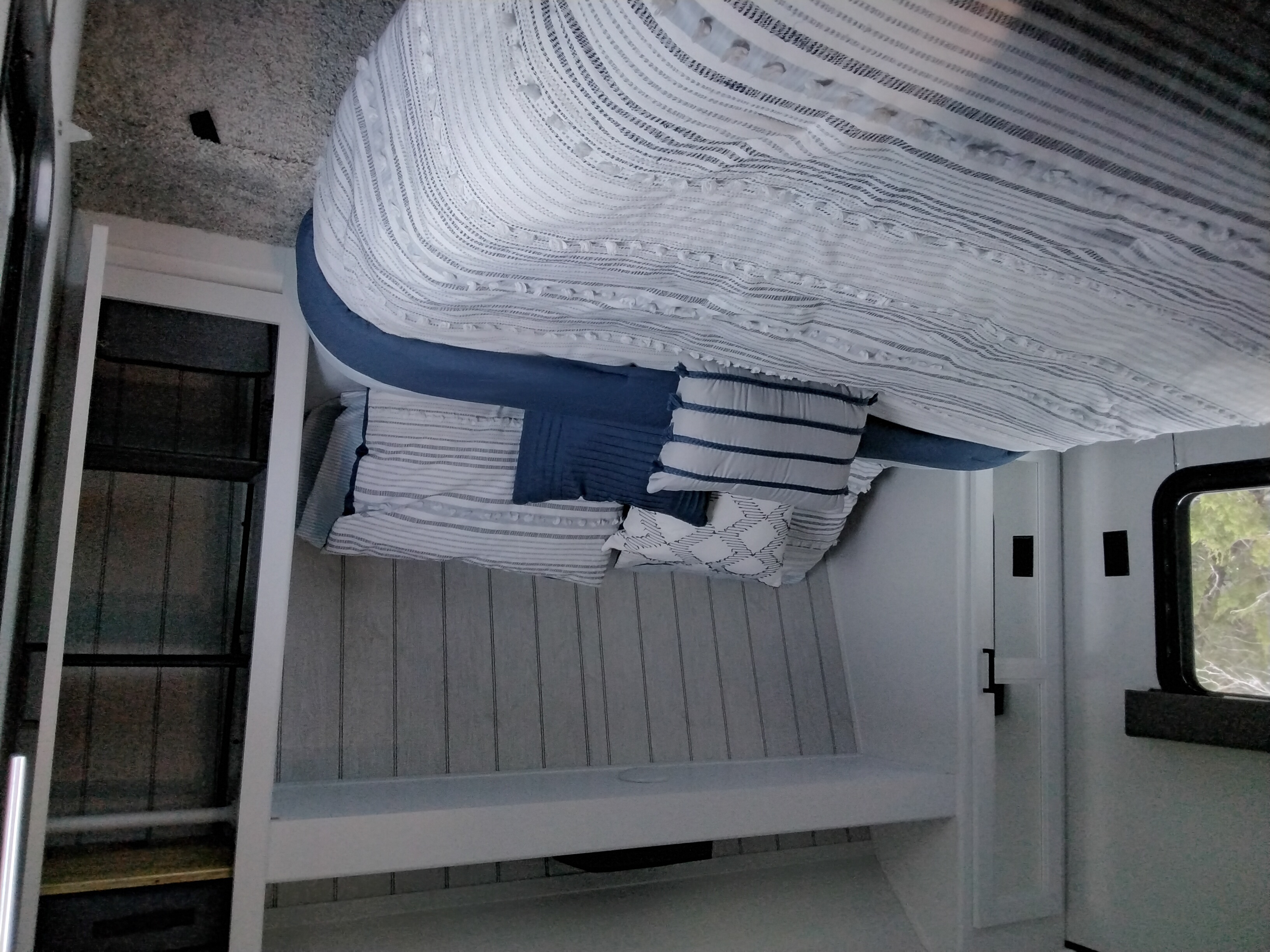 Experience comfort in this inviting RV rental bedroom, featuring soft blue and white bedding, pillows, and functional storage.. Keystone Hideout 262BH 2022