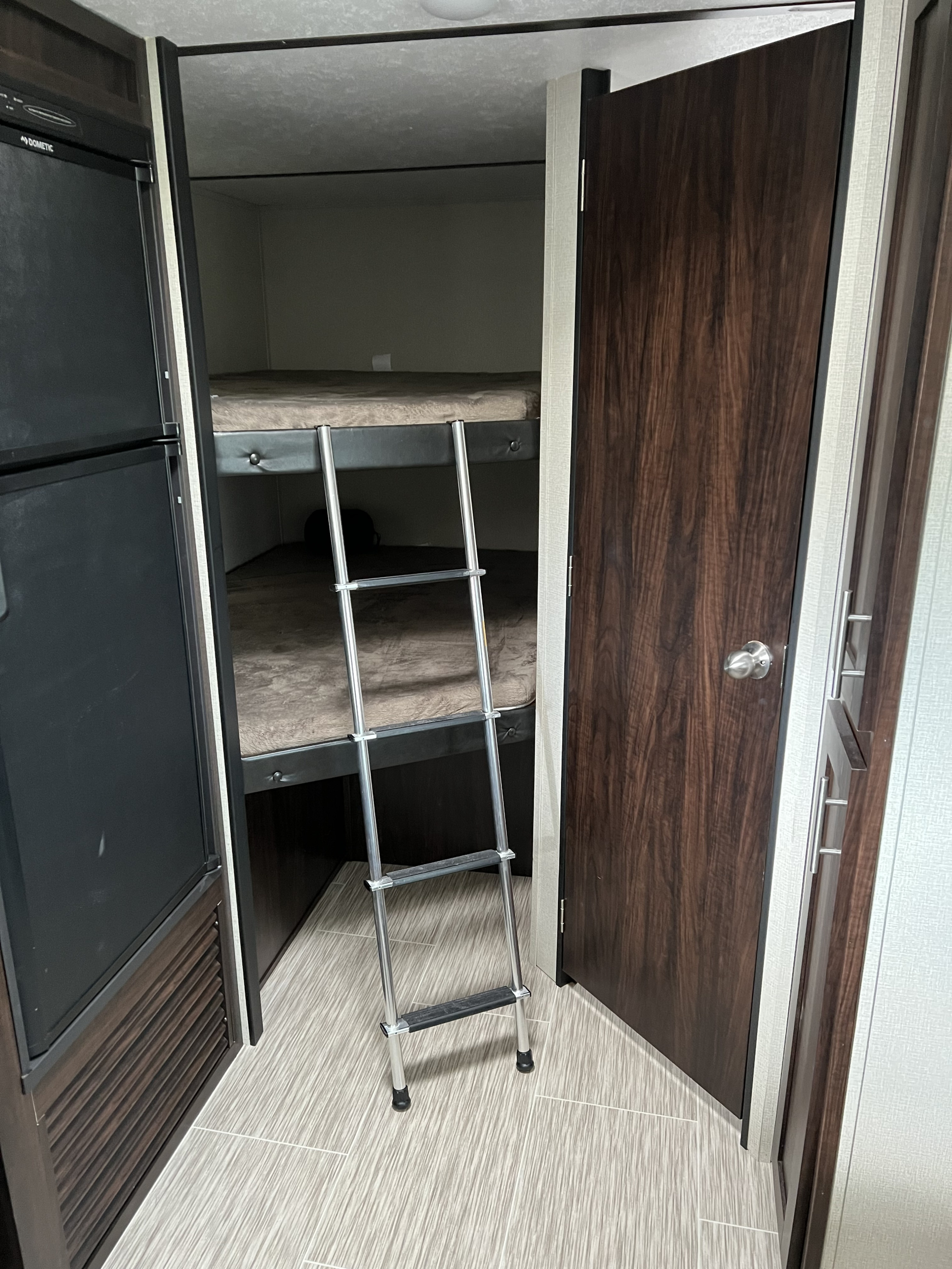 Inside this rv rental, cozy stacked bunk beds with a ladder provide sleeping space, alongside a refrigerator.. Forest River Tracer Breeze 2018