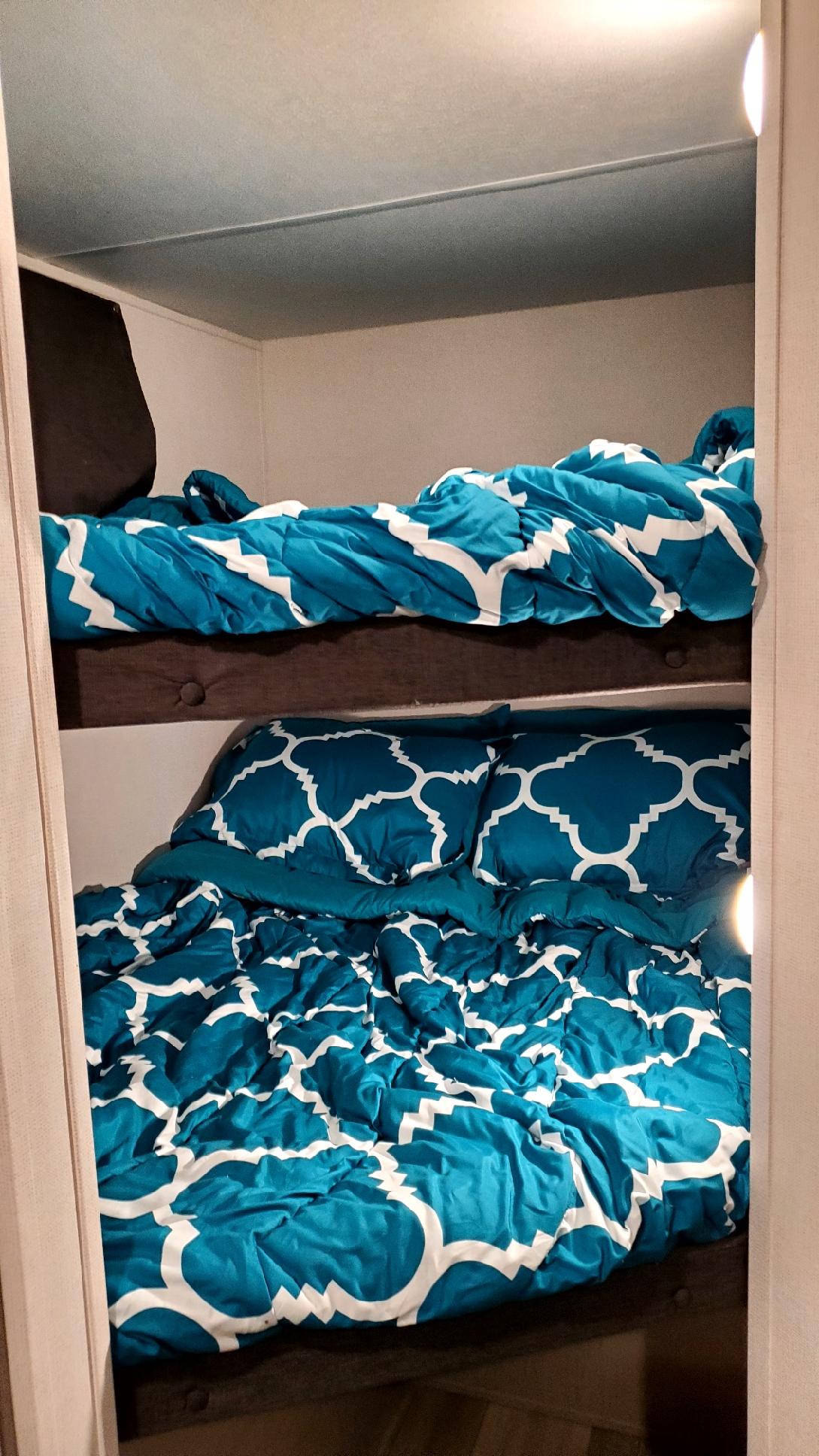 Cozy RV rental bunk beds featuring vibrant teal patterned bedding, perfect for comfortable sleeping arrangements in a compact space.. Forest River PRIME TIME 2022
