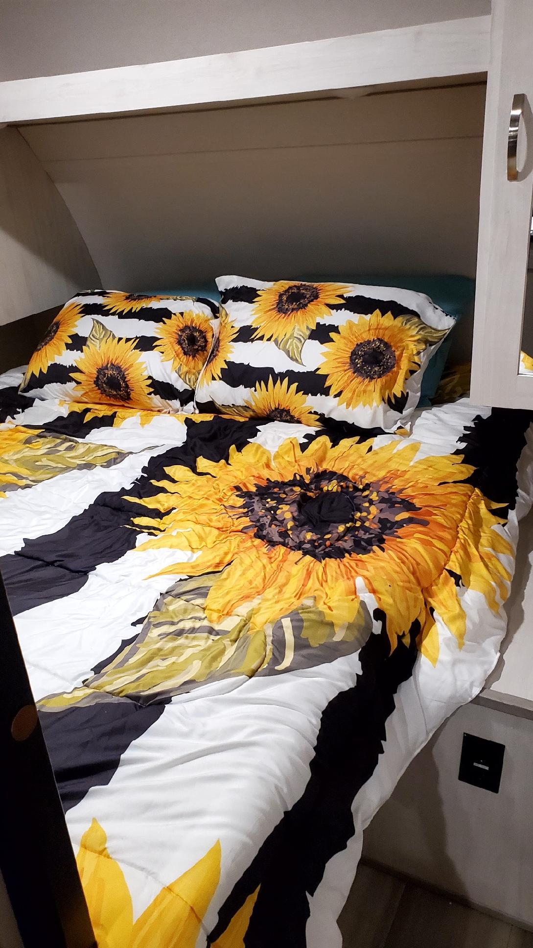 Cozy RV rental bed featuring a bright sunflower print comforter and pillows on black/white stripes.. Forest River PRIME TIME 2022