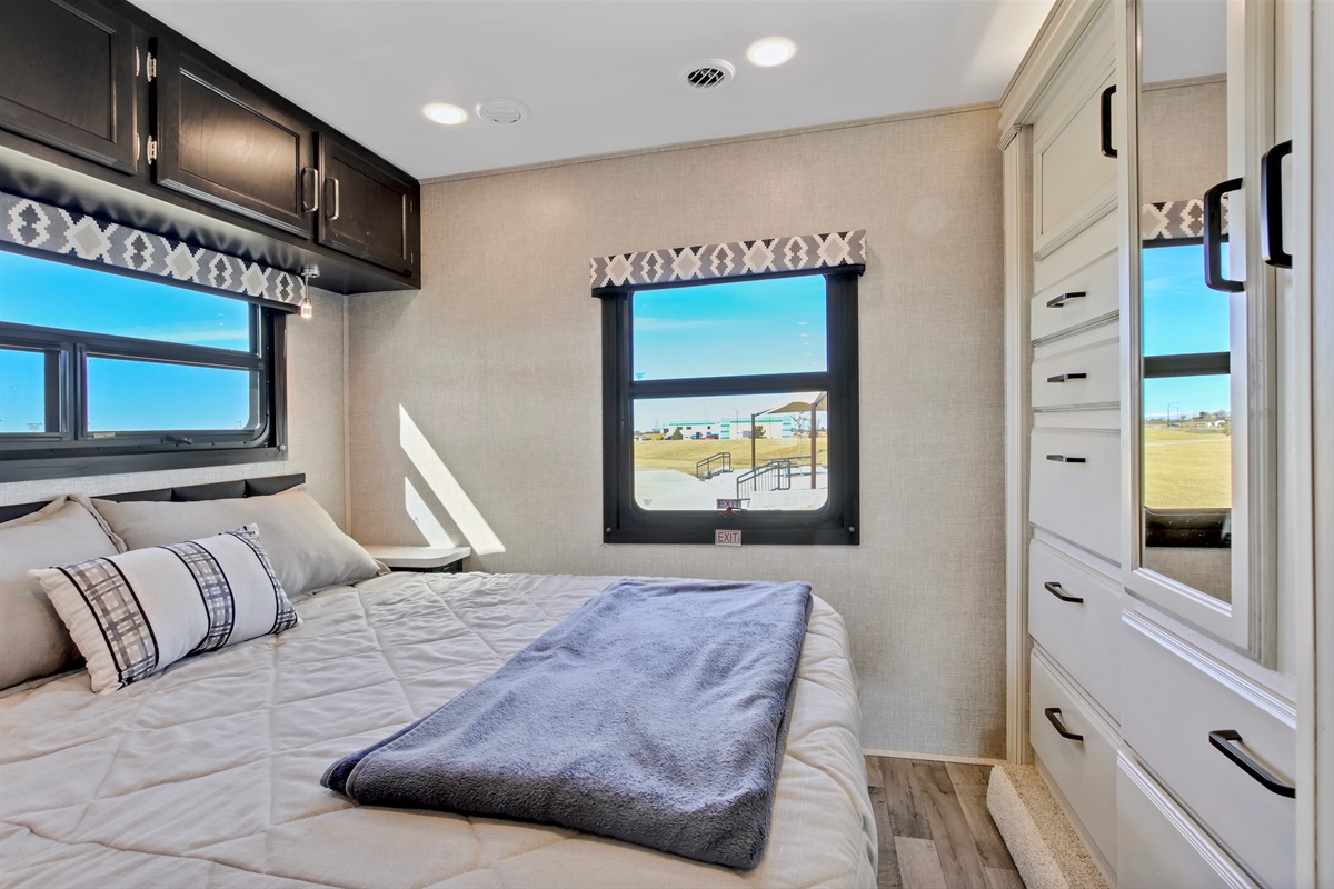 Inside a modern rv rental, this bedroom offers a comfy bed, ample storage, and scenic window views for your travels.. Jayco Redhawk 2022