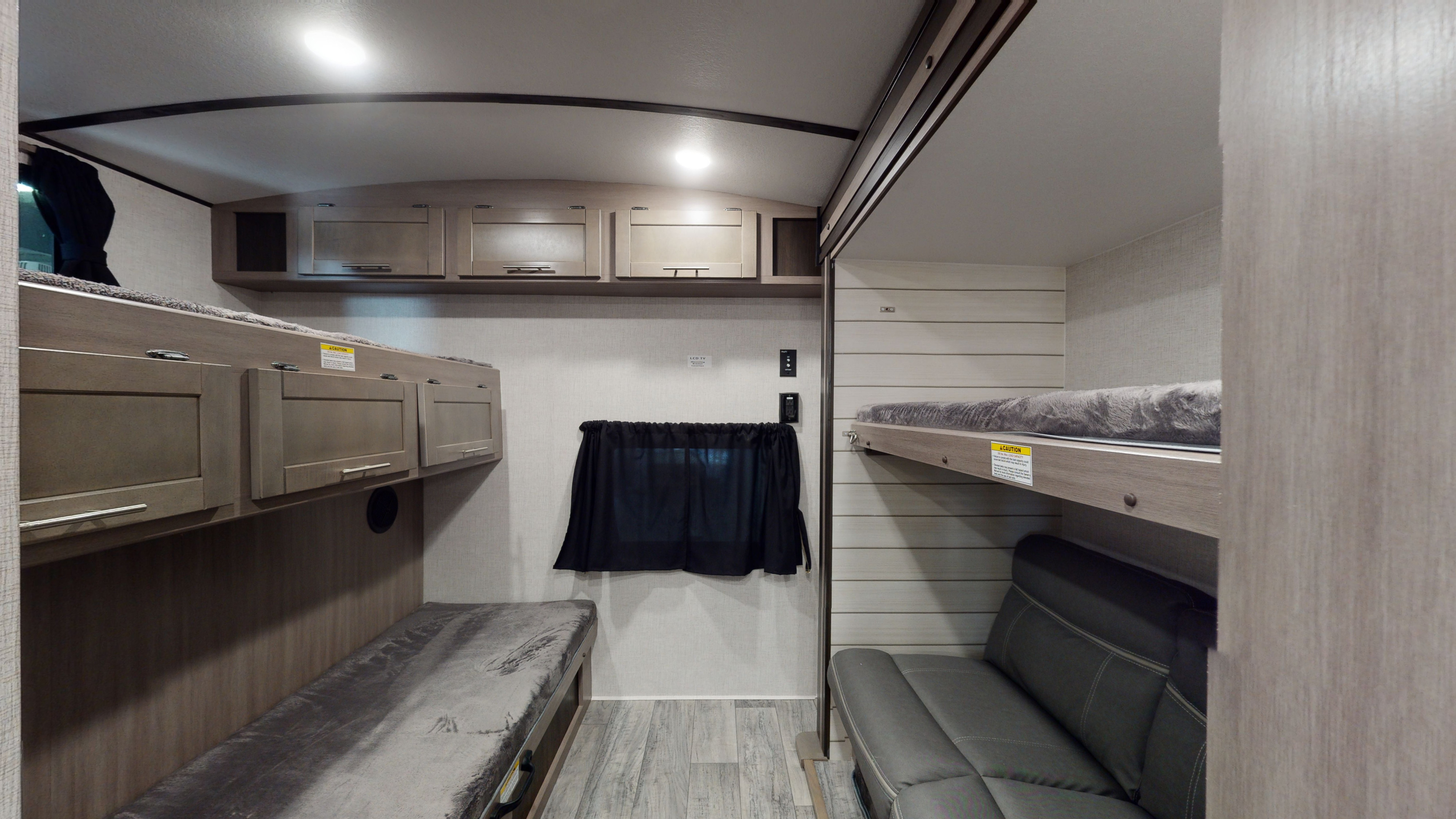 An RV rental's spacious bunkhouse interior, showing multiple beds, overhead cabinets, and a seating area.. Crossroads Sunset Trail Super Lite 2022