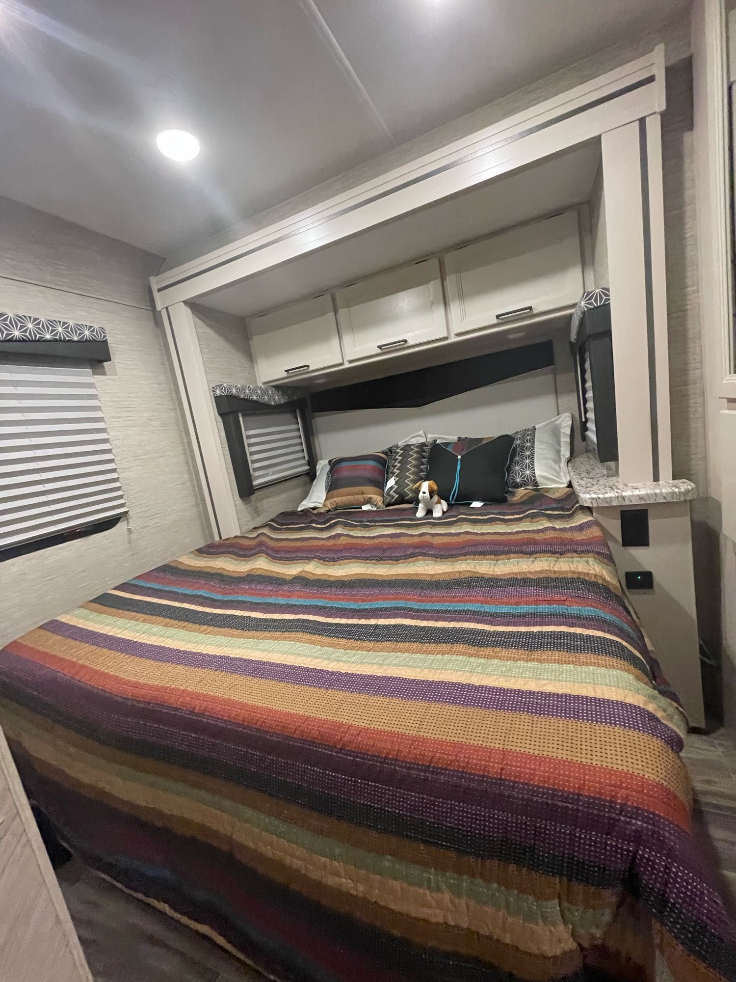 Cozy RV rental bedroom with a colorful striped bed, overhead cabinets, and blinds. Perfect for your next adventure.. THOR MOTOR COACH FREEDOM ELITE 22fef 2022