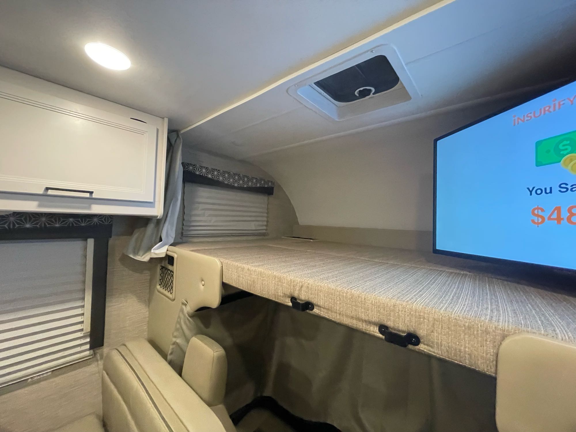 RV rental interior showing an overhead bunk bed with a TV, ceiling light, and window blinds for a cozy space.. THOR MOTOR COACH FREEDOM ELITE 22fef 2022