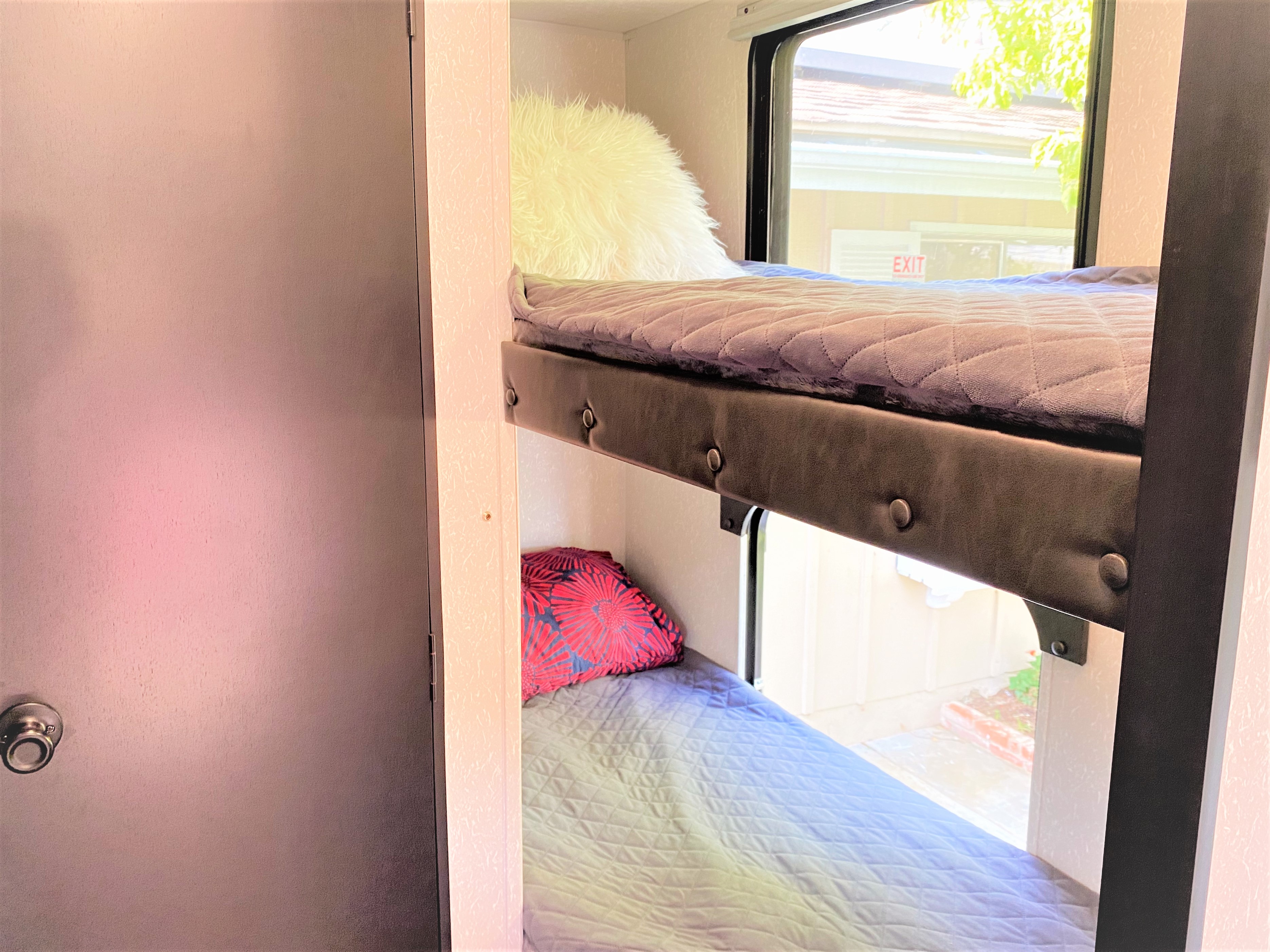 Comfortable bunk beds in this RV rental, featuring quilted bedding, soft pillows, and a bright window view for travelers.. Forest River Cherokee Wolf Pup 2022