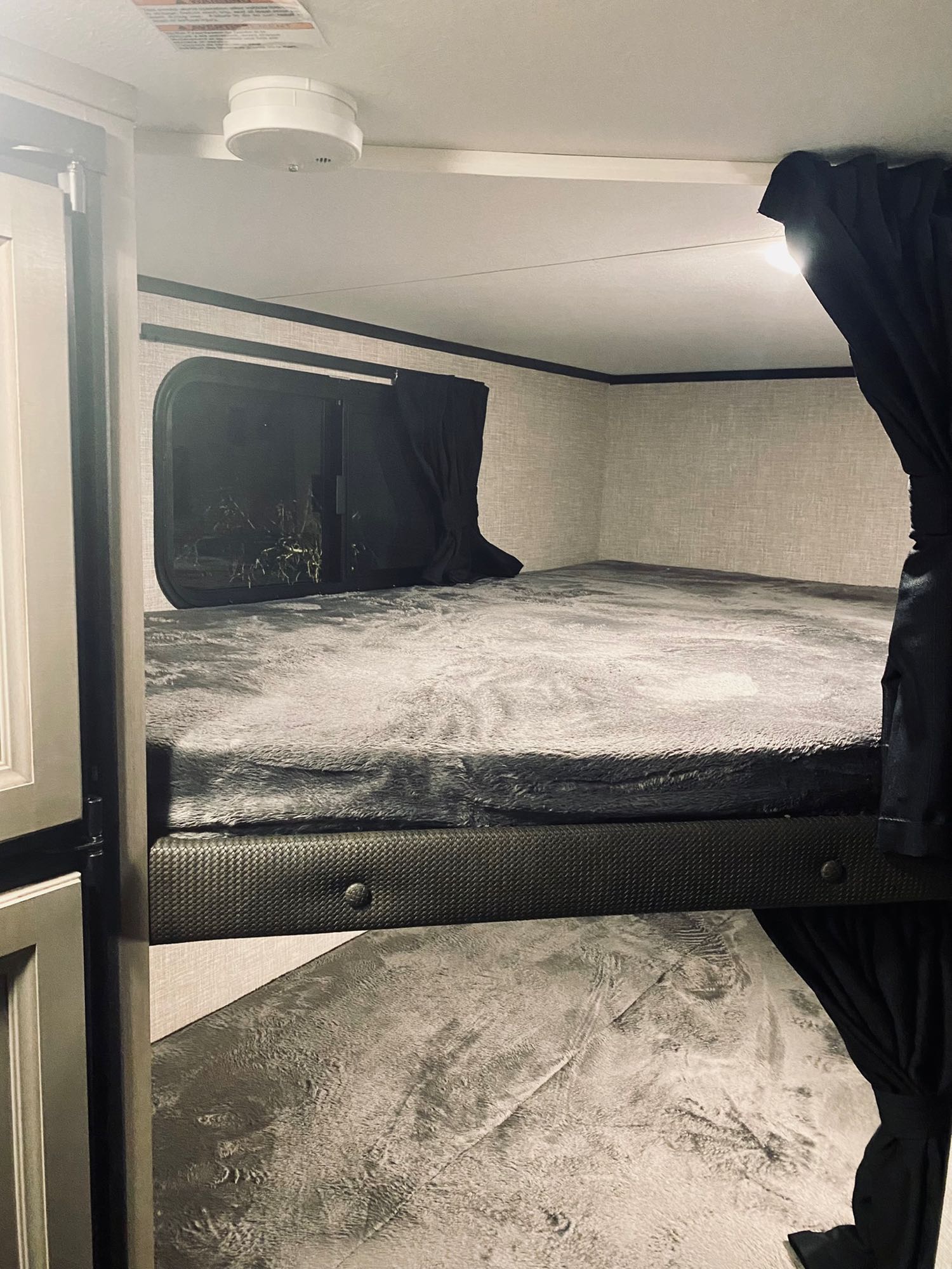 This RV rental offers compact sleeping with an upper bunk, grey bedding, window, and ceiling smoke detector.. jayco Jay feather 199mbs 2022