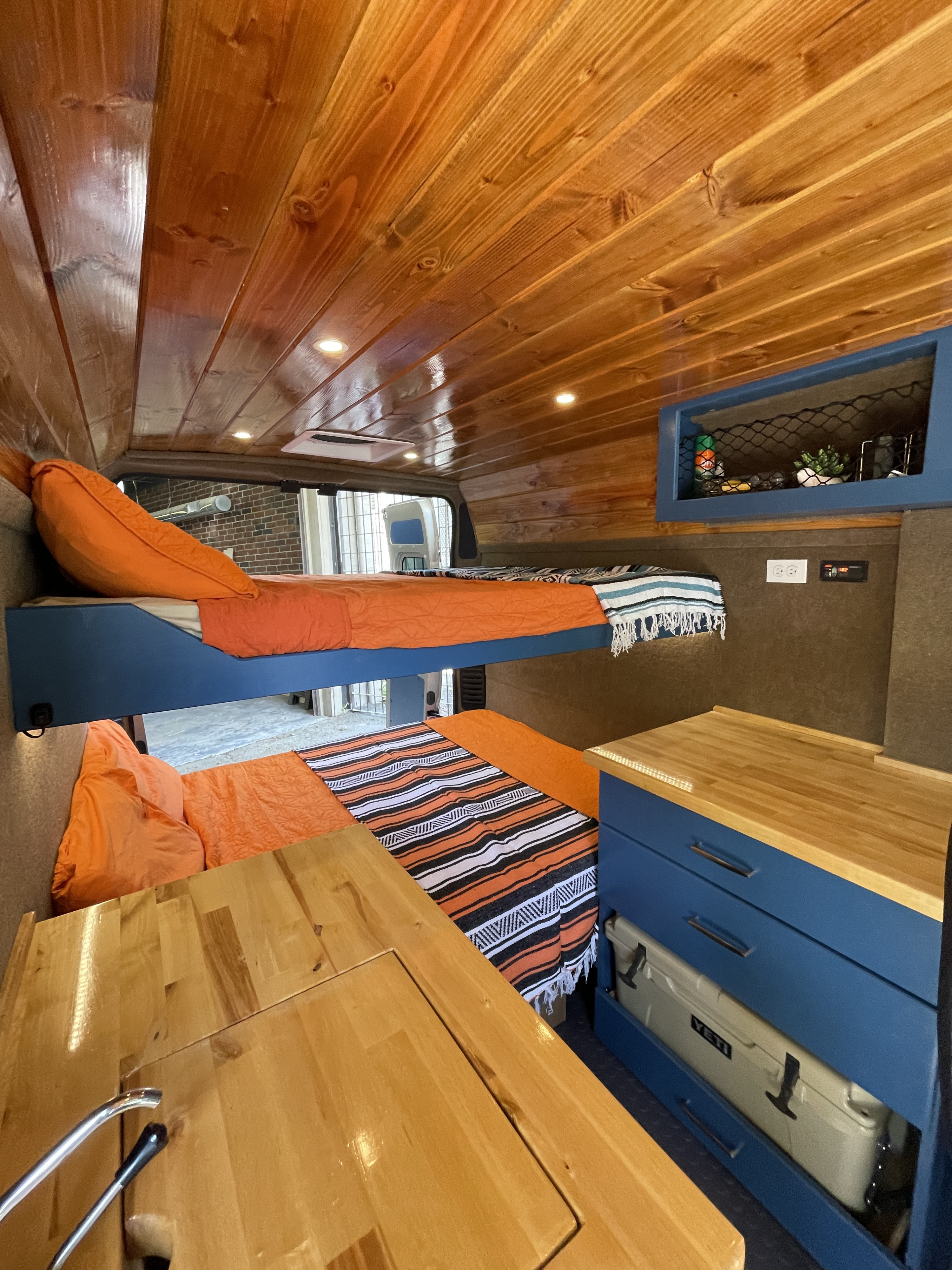 Explore this RV rental's comfy interior: wooden ceiling, bunk beds, and sleek kitchenette with storage.. Ram Promaster 2021