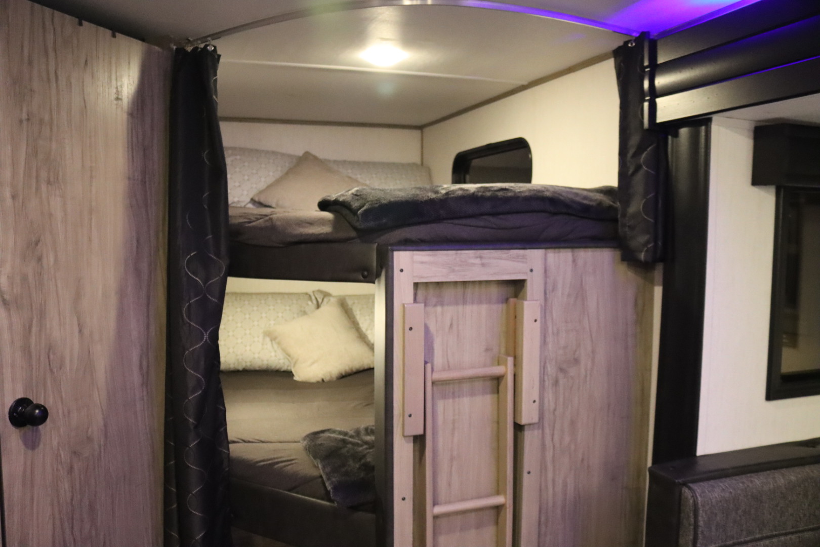 Inside an RV rental: bunk beds with a ladder and privacy curtains, offering comfortable sleeping for family trips.. Forest River Cherokee Alpha Wolf 2022