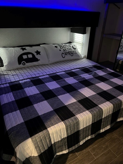 Cozy RV rental bedroom with buffalo check bedding and camper pillows, perfect for a memorable camping trip.. Forest River Cherokee Arctic Wolf 2022