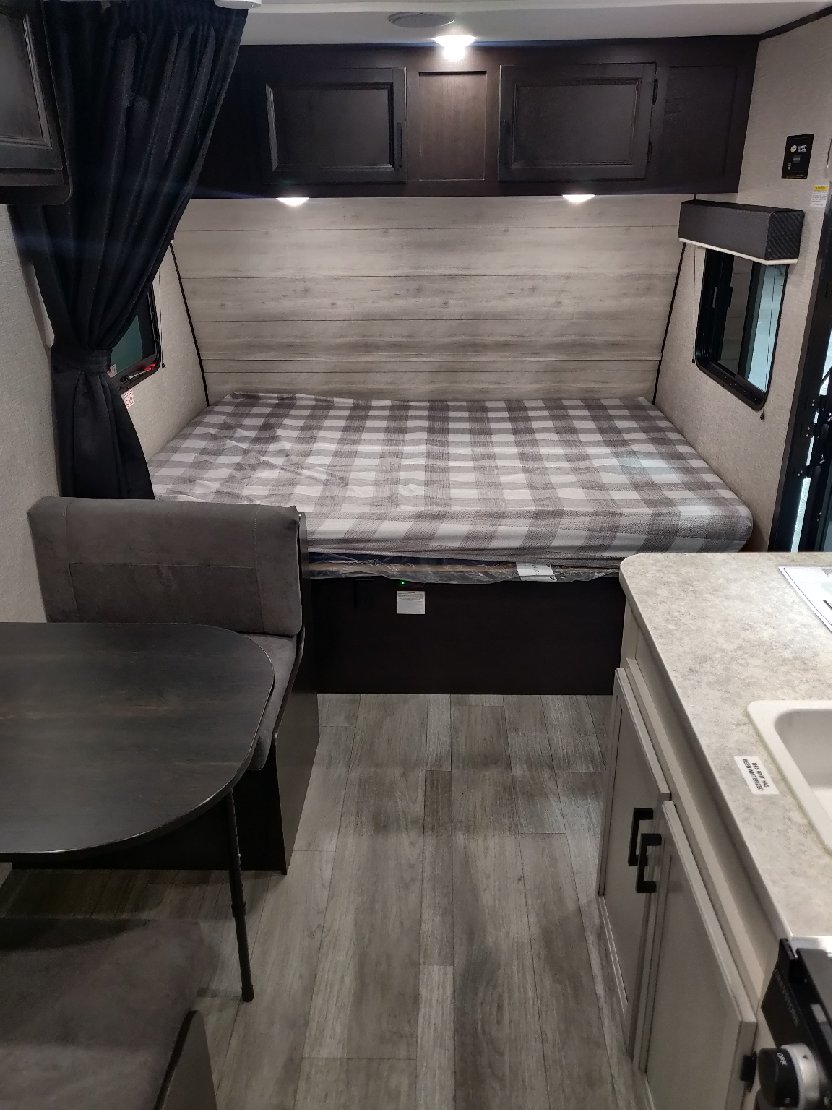 Cozy RV rental interior with a comfortable bed, kitchenette, and dining area, ideal for travel.. Jayco Jay Flight SLX 2022