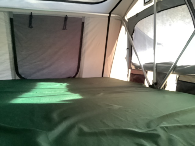Interior of an RV rental sleeping space. Features a green mattress, mesh window, and support poles. Ready for camping adventures.. Custom Toyota Sequoia four wheel drive 2005