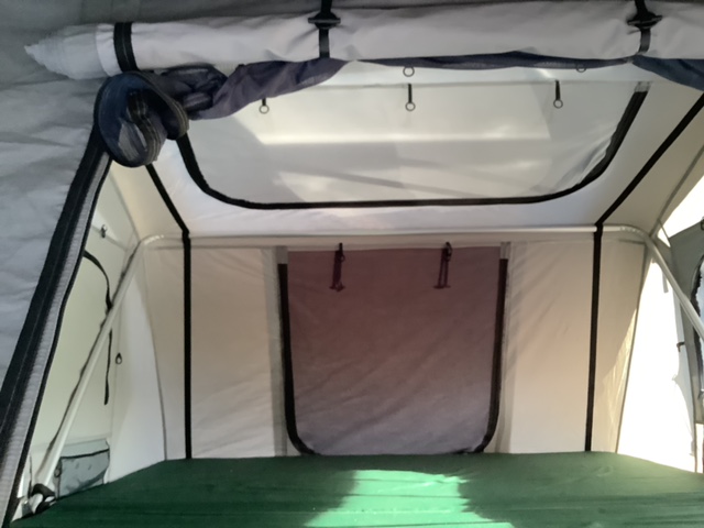 RV rental rooftop tent interior: Bright sleeping area with green mattress & overhead mesh storage. Ideal for camping.. Custom Toyota Sequoia four wheel drive 2005