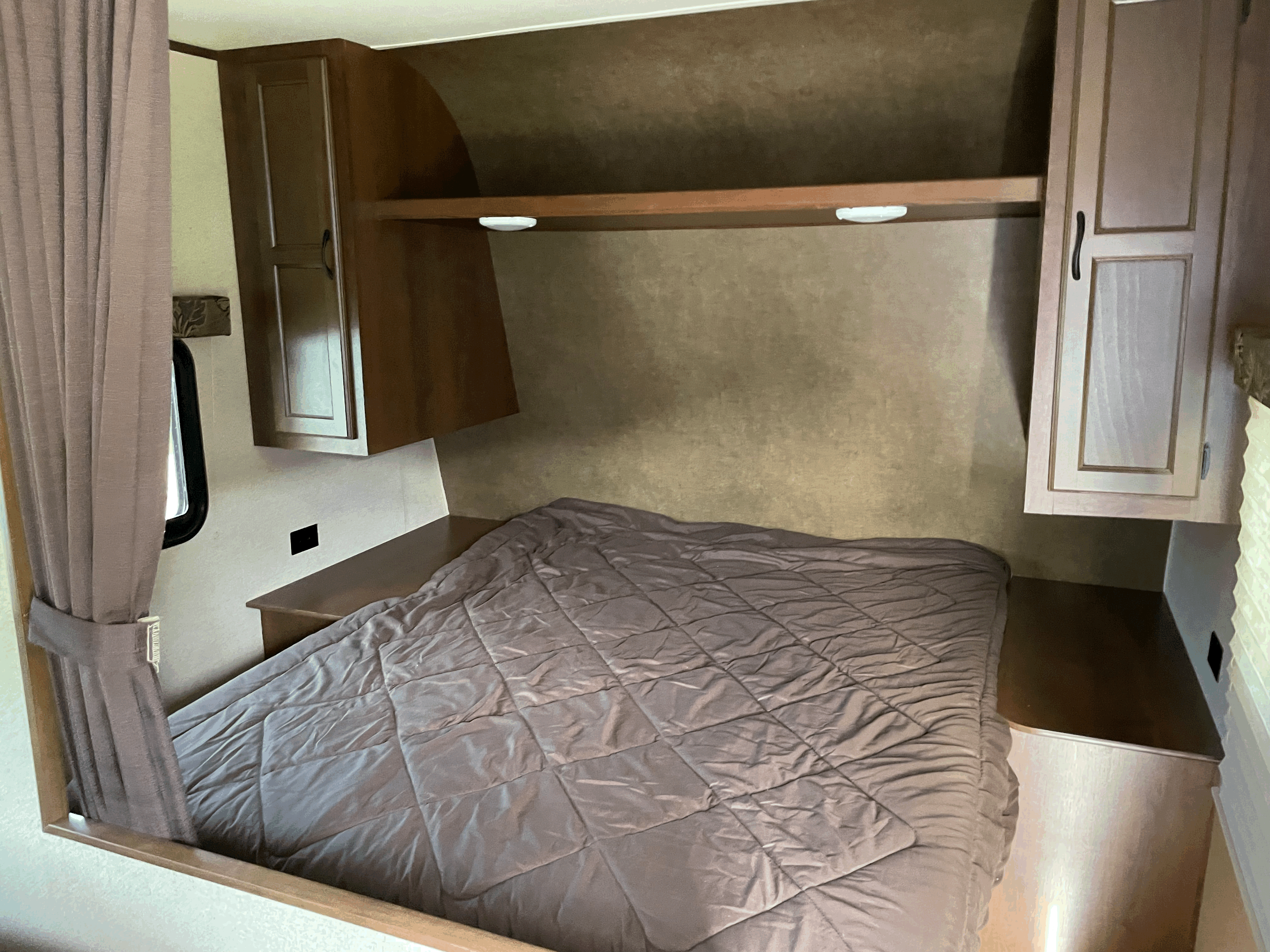 Cozy RV rental bedroom with a comfy quilted bed, overhead storage, and bedside window.. Jayco Jay Feather Ultra Lite SLX 2015