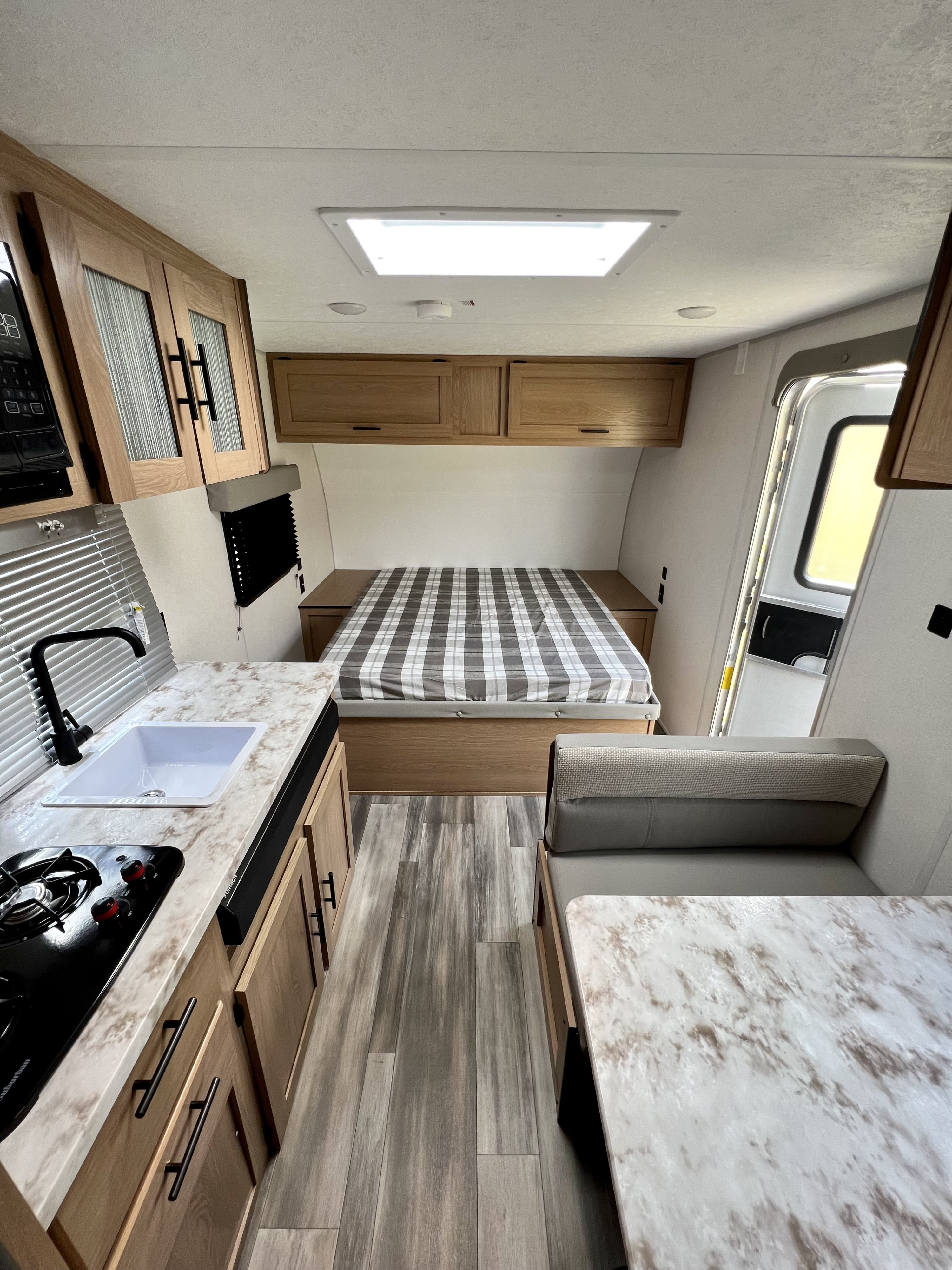Cozy RV rental interior featuring a bed, kitchen with sink & stove, and a dinette.. Forest River Prime Time Avenger LT 16FQ 2022