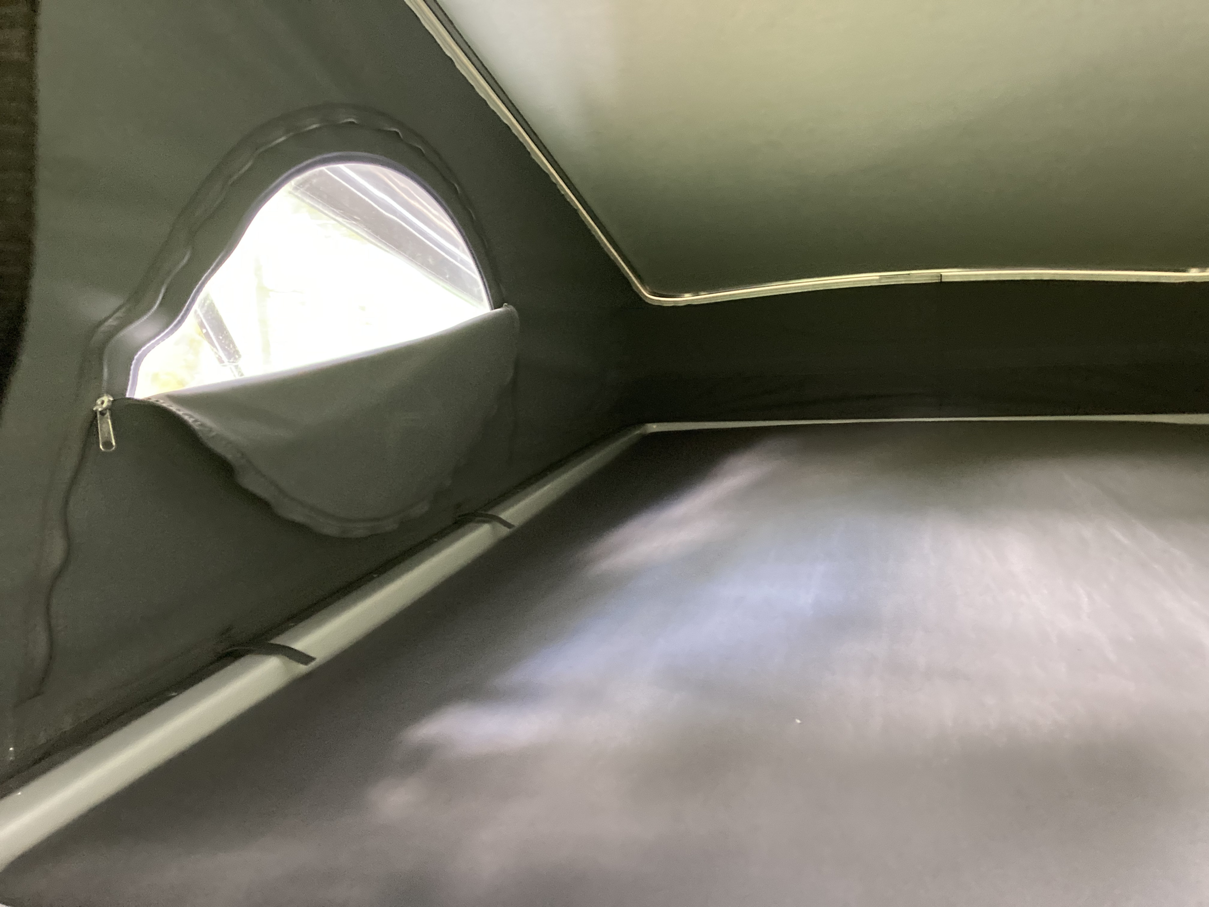 Interior of an RV rental: dark fabric walls, a bright window, and a flat sleeping area, ready for adventure.. Winnebago Solis 2022