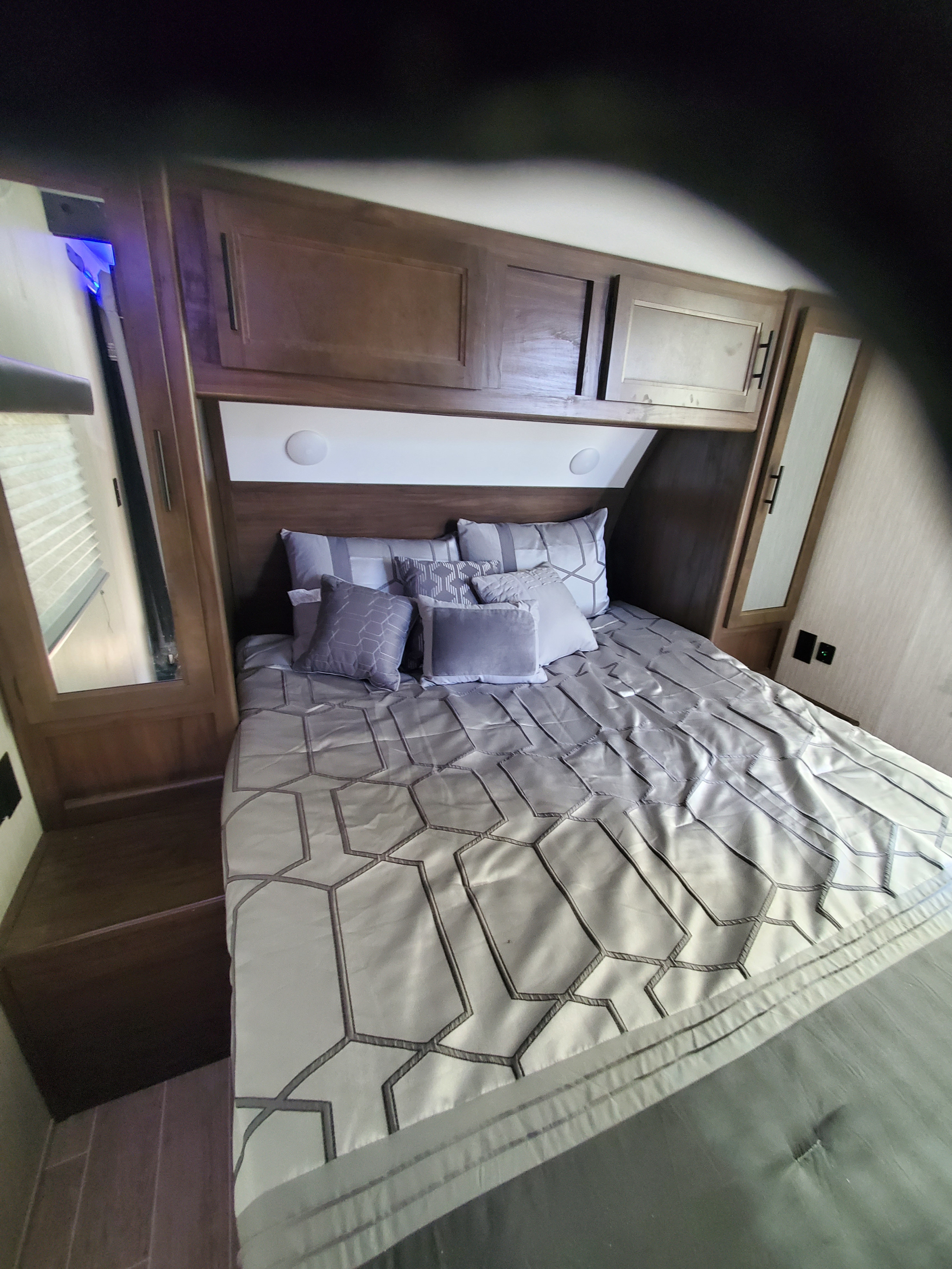 Compact and modern RV rental bedroom featuring a grey bed, overhead storage, and integrated lighting.. Forest River Cherokee Grey Wolf 2021
