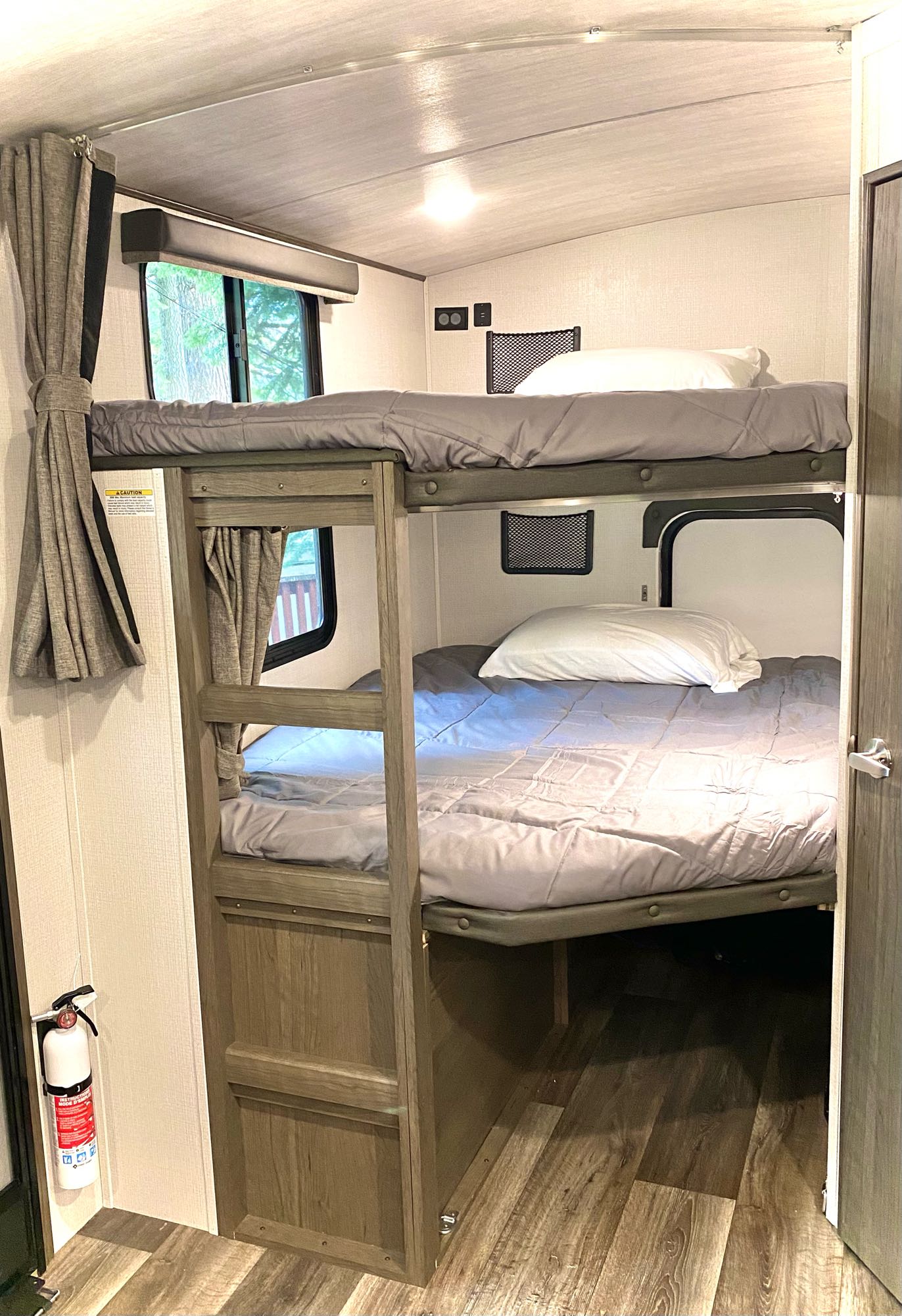Explore a comfy RV rental bunk bed setup. This camper interior features two sleeping tiers & a window, ideal for families.. Keystone Cougar Half-Ton 2022