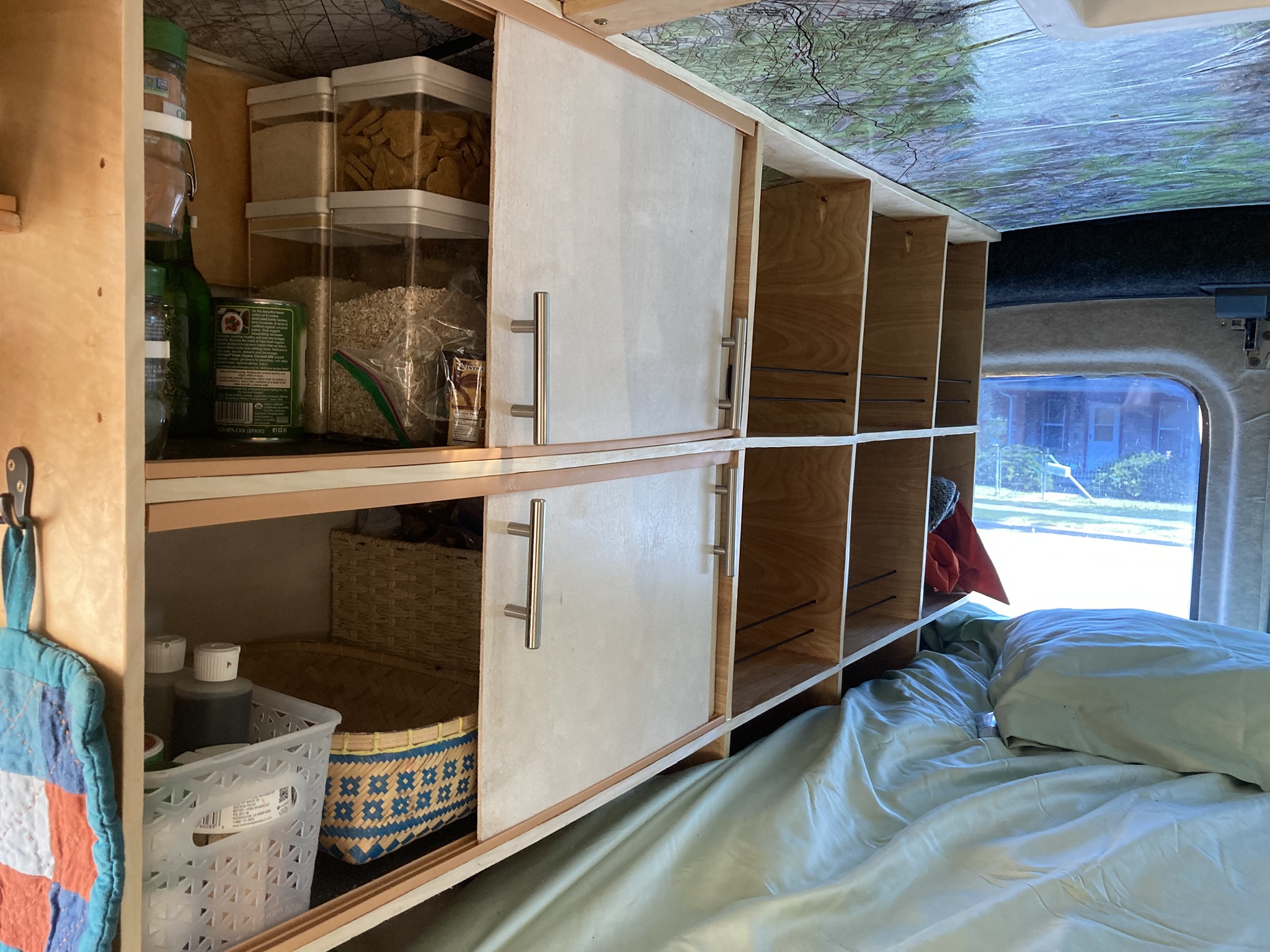 Custom RV rental interior with organized storage shelves, sliding doors, and a cozy bed for travel adventures.. Ford Transit Custom 2015