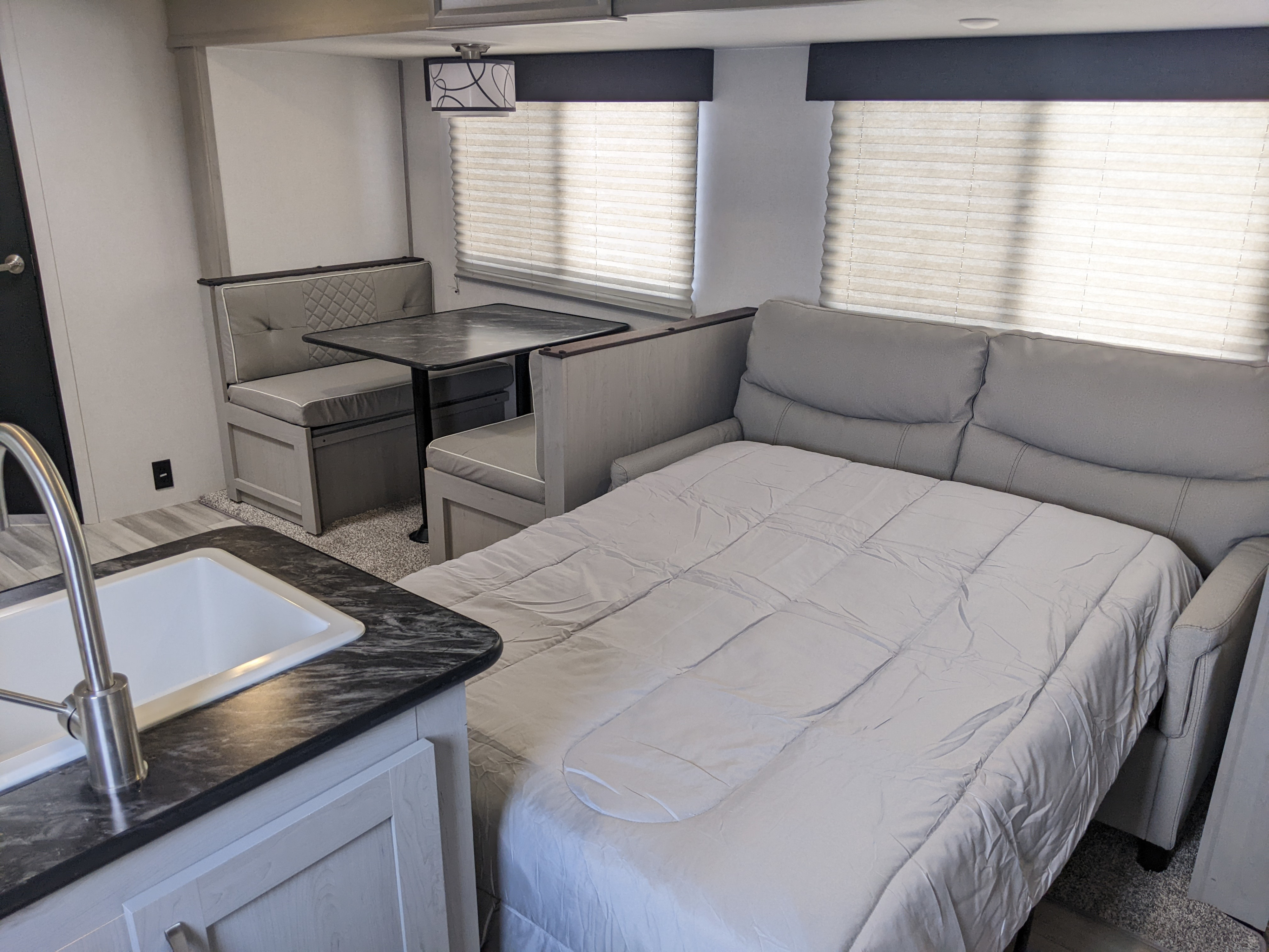 Inside this modern RV rental, find a comfortable dinette, functional kitchen sink, and a sofa easily converting to a bed.. Other Other 2022