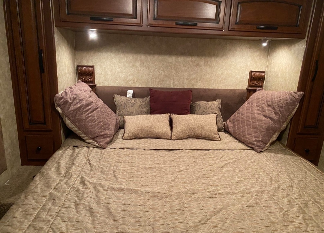Cozy RV rental bedroom featuring a comfortable bed with various pillows and convenient built-in storage cabinets.. Tioga Tioga Motorhome 2012