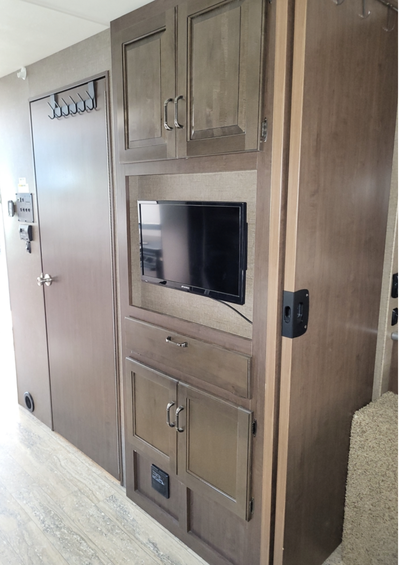 RV rental's cozy interior features practical wood cabinets, built-in TV, and handy door hooks for travelers.. Thor Hurricane 2017