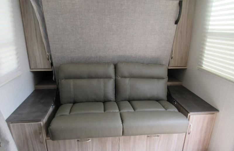 Compact RV rental interior featuring a convertible sofa, storage cabinets, and a murphy bed for efficient space.. Minnie Micro Minnie 2022