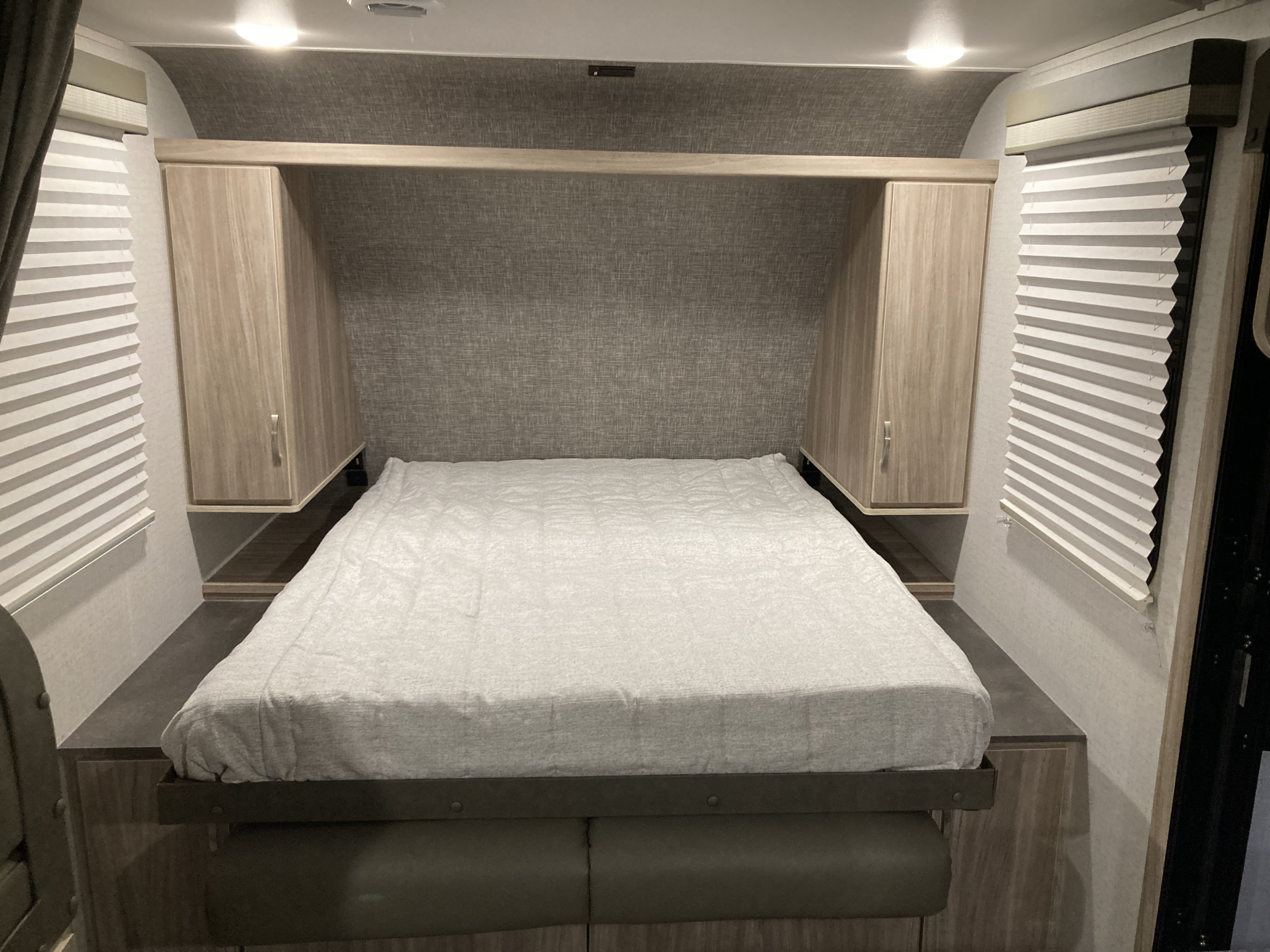 Inside an RV rental: a compact bedroom with a comfortable bed, built-in storage, and window blinds.. Winnebago Micro Minnie 2022