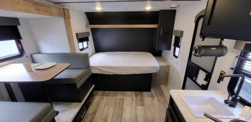Explore this modern RV rental interior: a comfy bed, dinette, and well-equipped kitchen await your next adventure!. Keystone Springdale 2022