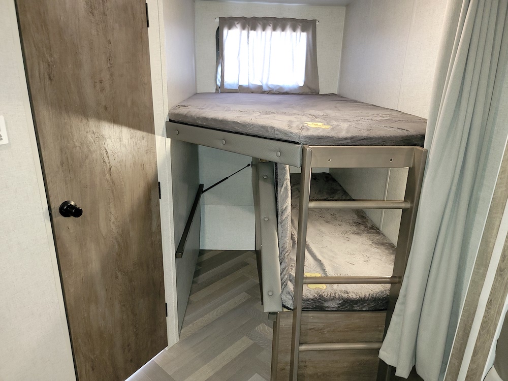 RV rental with cozy bunk beds and a door. Ideal for family sleeping in a travel trailer interior.. Forest River Salem 2021