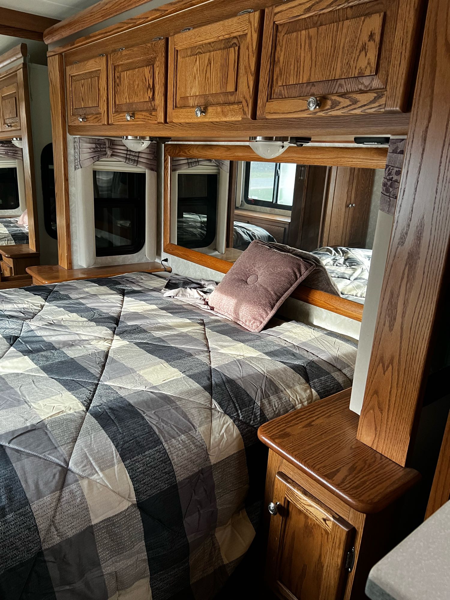 Cozy RV rental bedroom featuring a comfortable bed with plaid bedding, wooden cabinets, and reflective mirrors.. Allegro Allegro Bay 2004