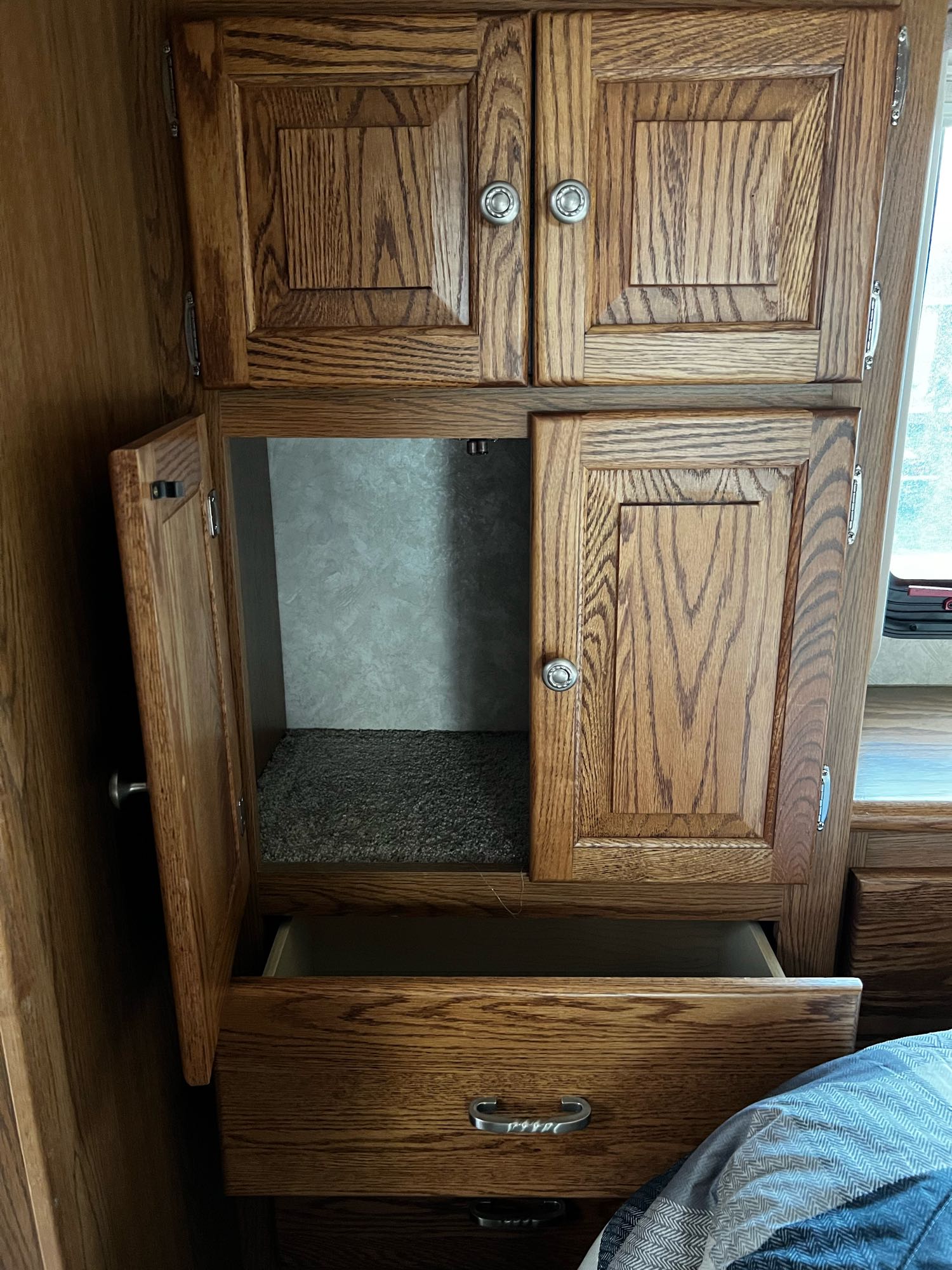 Spacious RV rental interior: wooden cabinets, storage, and drawers. A cabinet is open revealing a carpeted floor.. Allegro Allegro Bay 2004