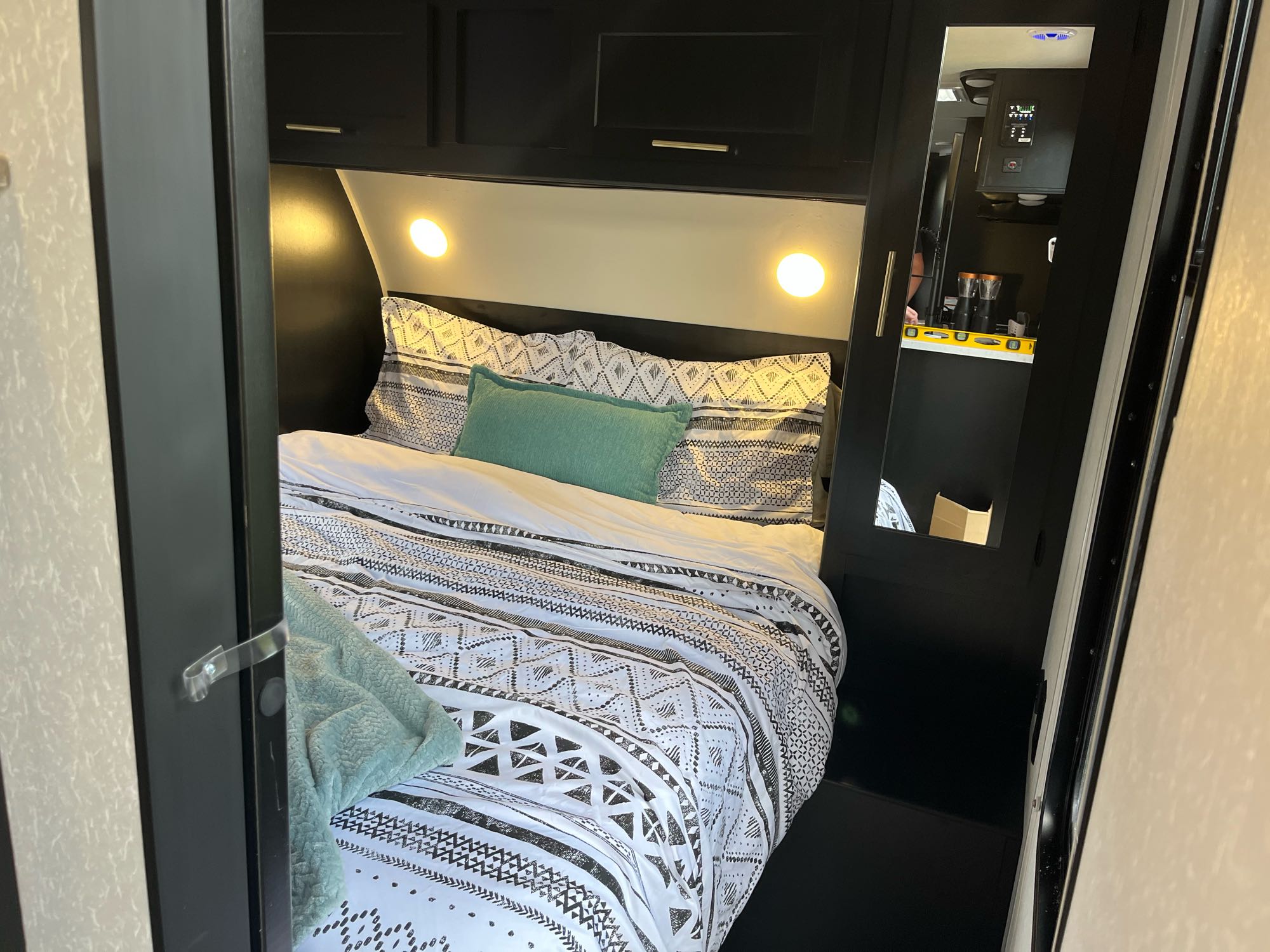 Step inside this cozy RV rental bedroom. Features dark wood, patterned bedding, and warm overhead lights.. Forest River Cherokee Grey Wolf 2022