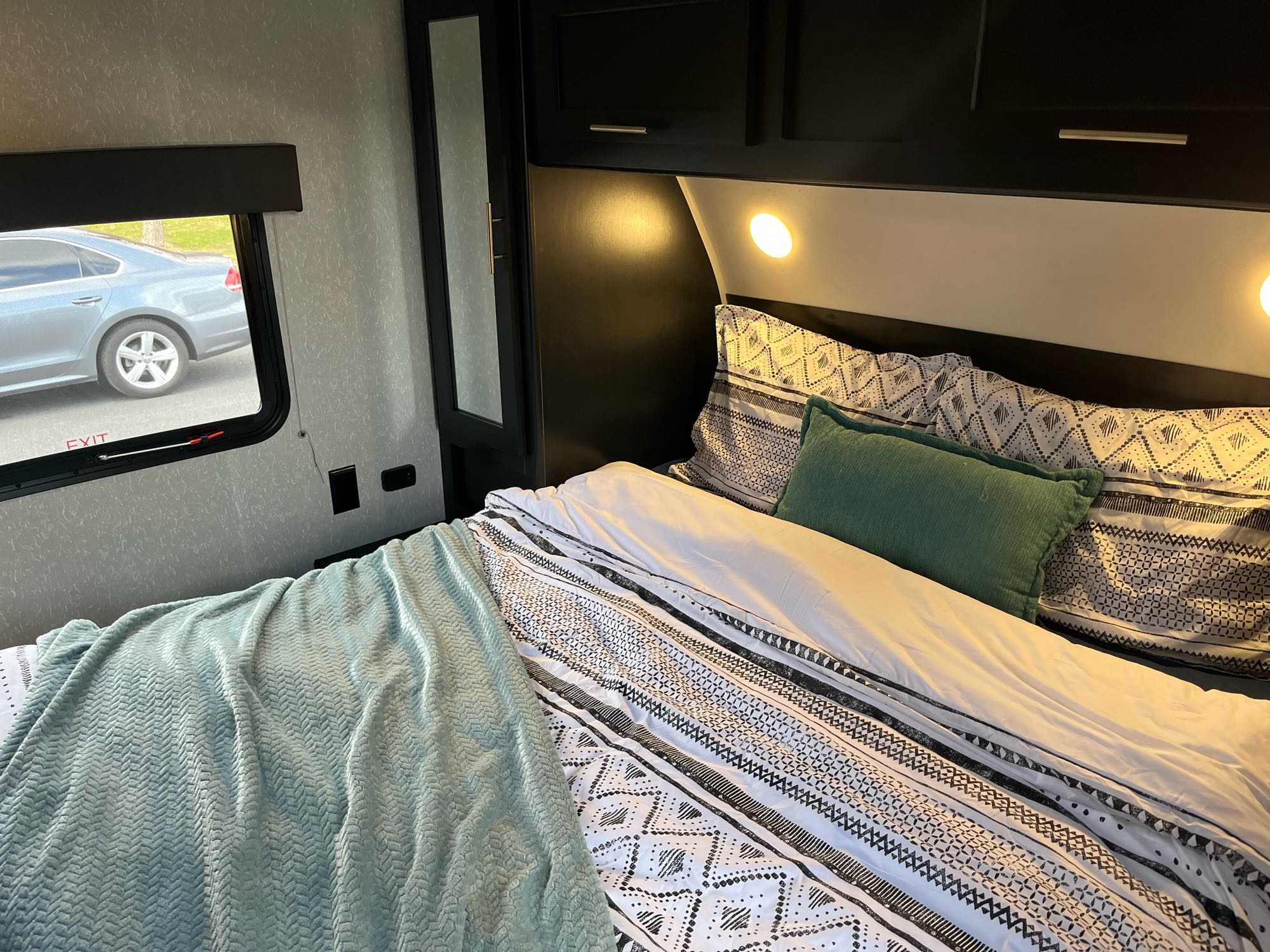 Cozy RV rental bedroom features a comfy bed with geometric bedding, ambient lighting, and a window view for travel.. Forest River Cherokee Grey Wolf 2022