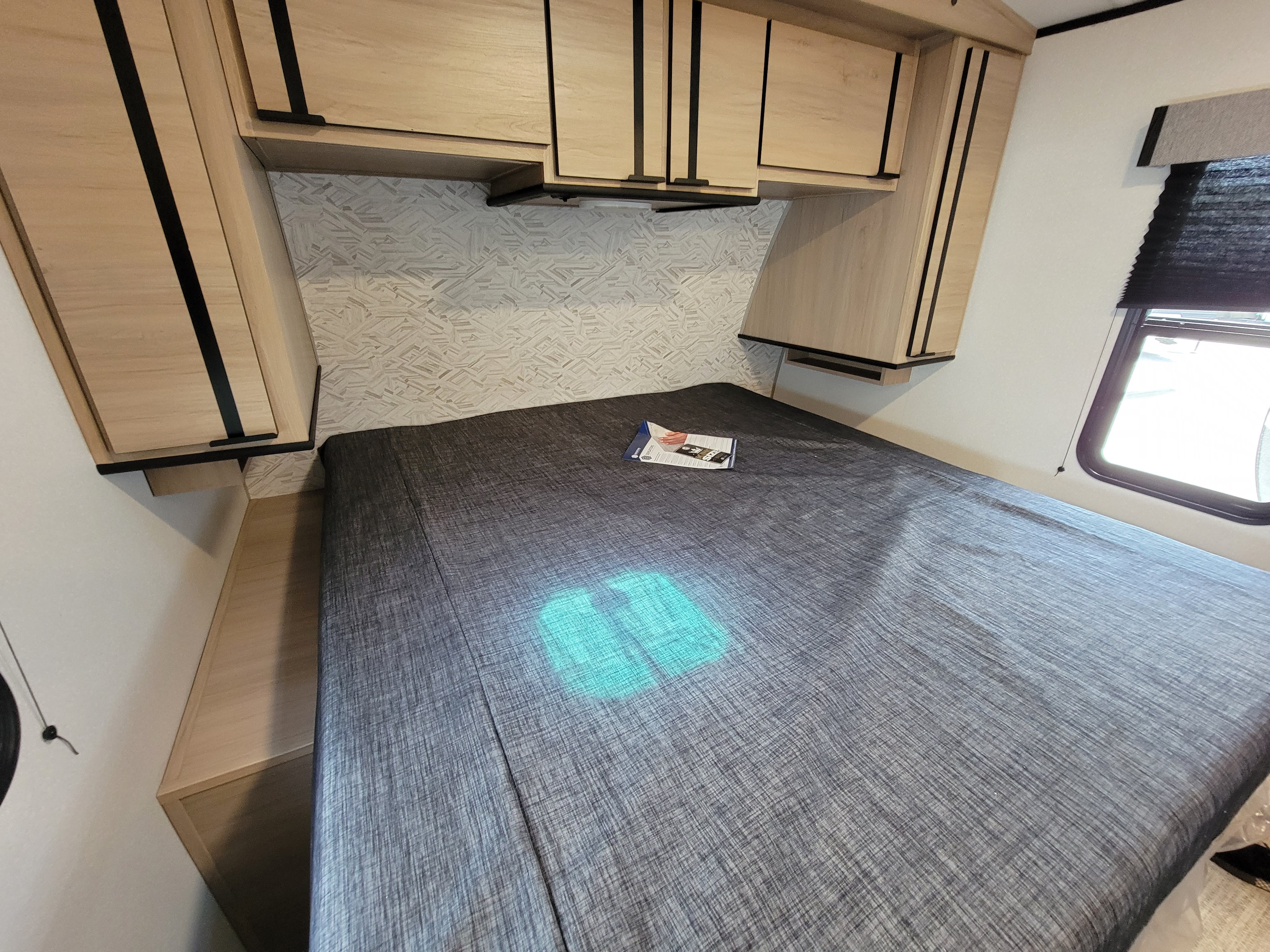 RV rental interior featuring a bedroom with a patterned headboard wall, bed, and light wood overhead storage.. Cruiser Rv Corp Radiance 30ds 2021