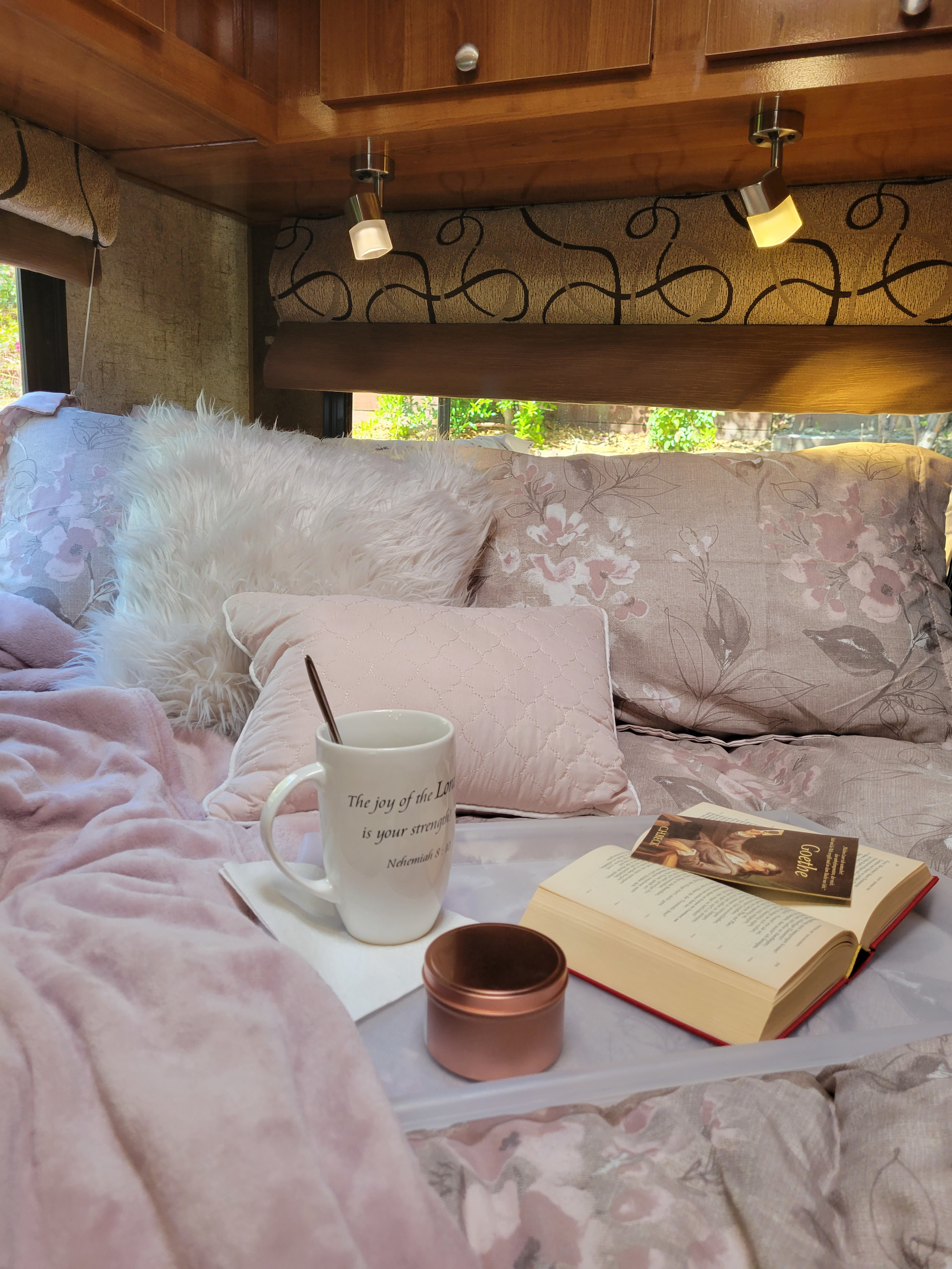 Cozy RV rental bedroom with a book, mug, and fluffy pillows on a bed, ready for relaxation.. Coachman Leprechaun 2018