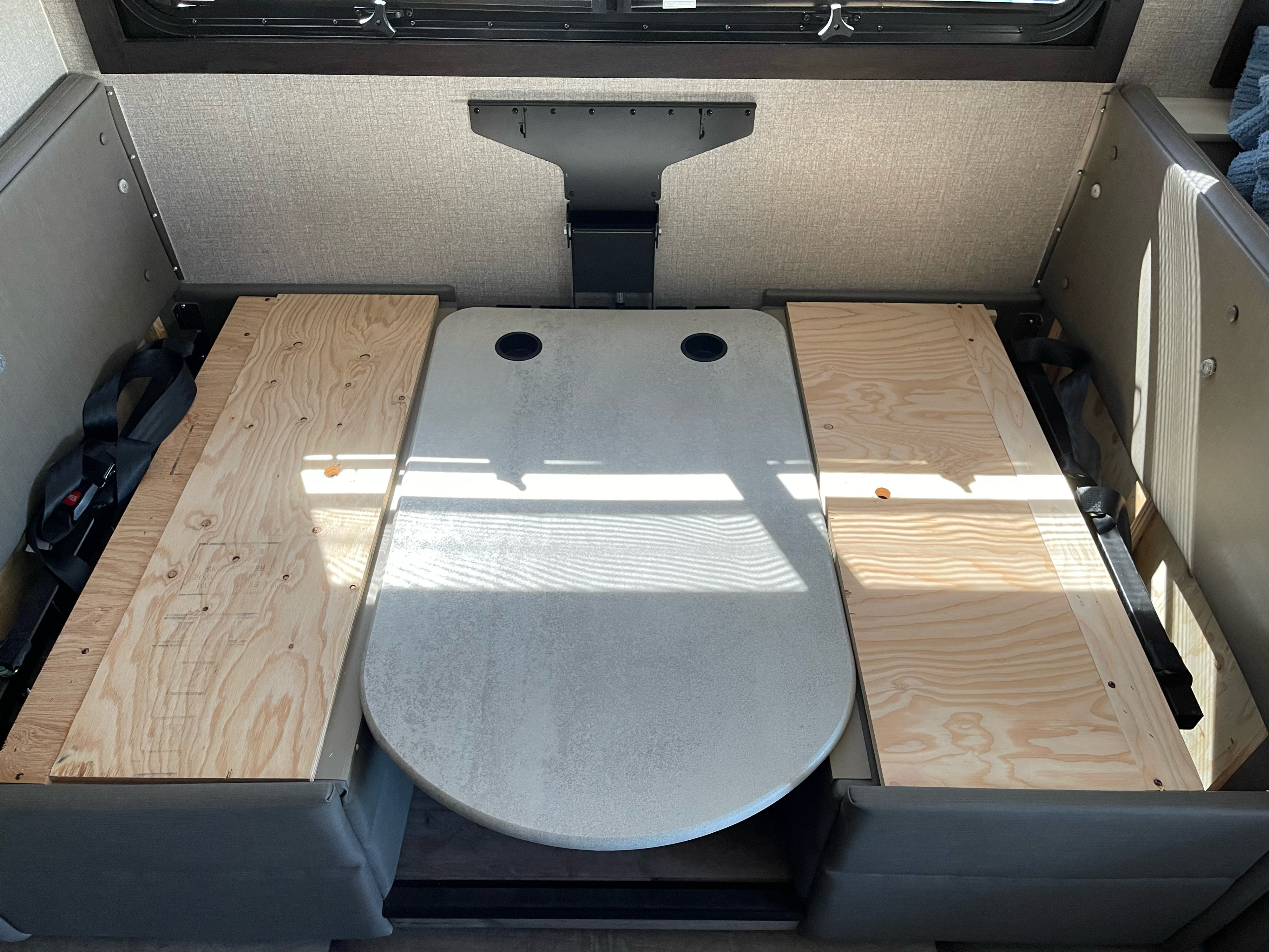 Inside an RV rental: a dinette table lowers between wooden bed platforms, creating a cozy sleep area.. Jayco Precept 2021