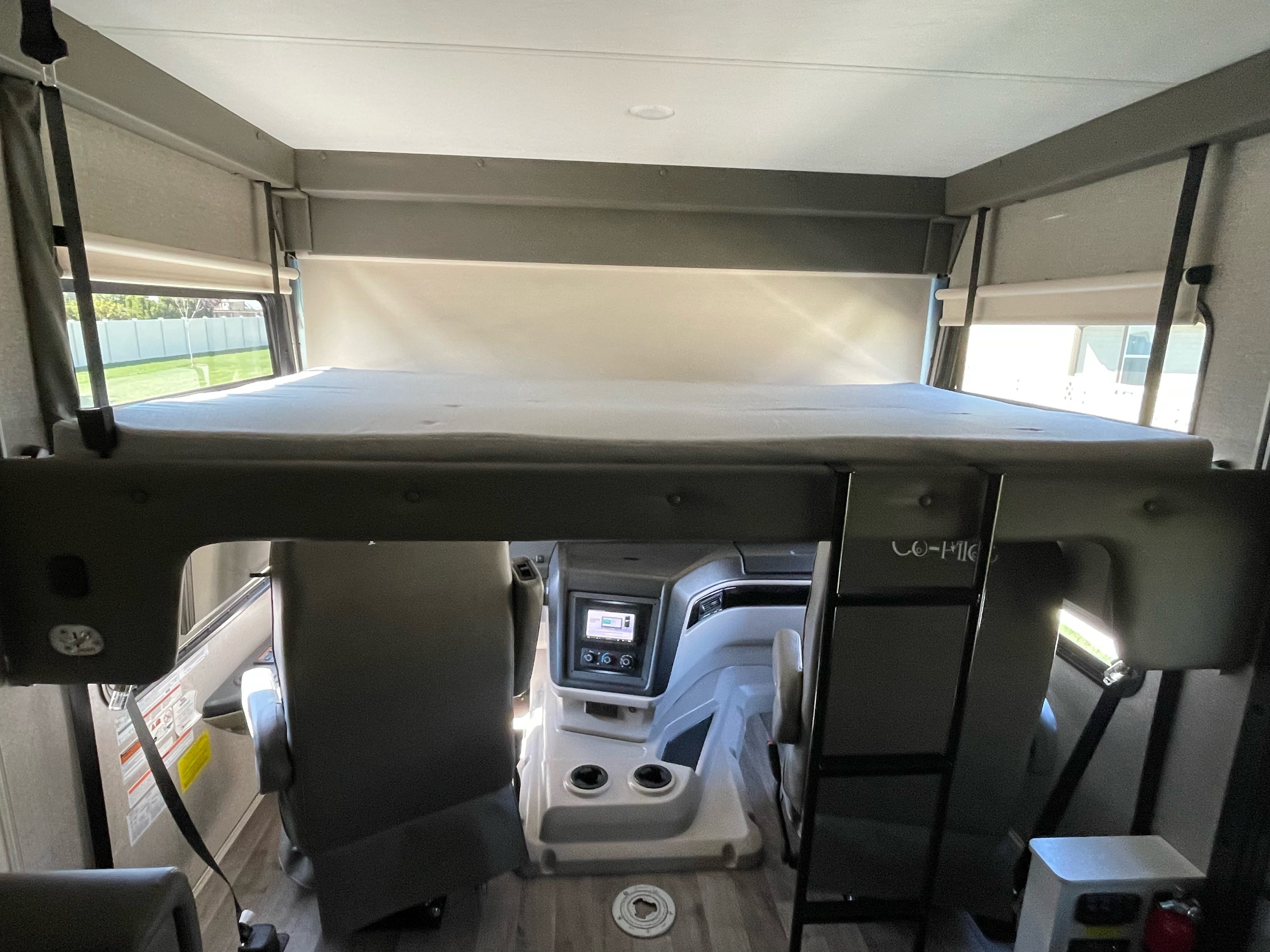 Spacious over-cab bunk in an RV rental motorhome, offering extra sleeping space above the modern driver's cockpit area.. Jayco Precept 2021