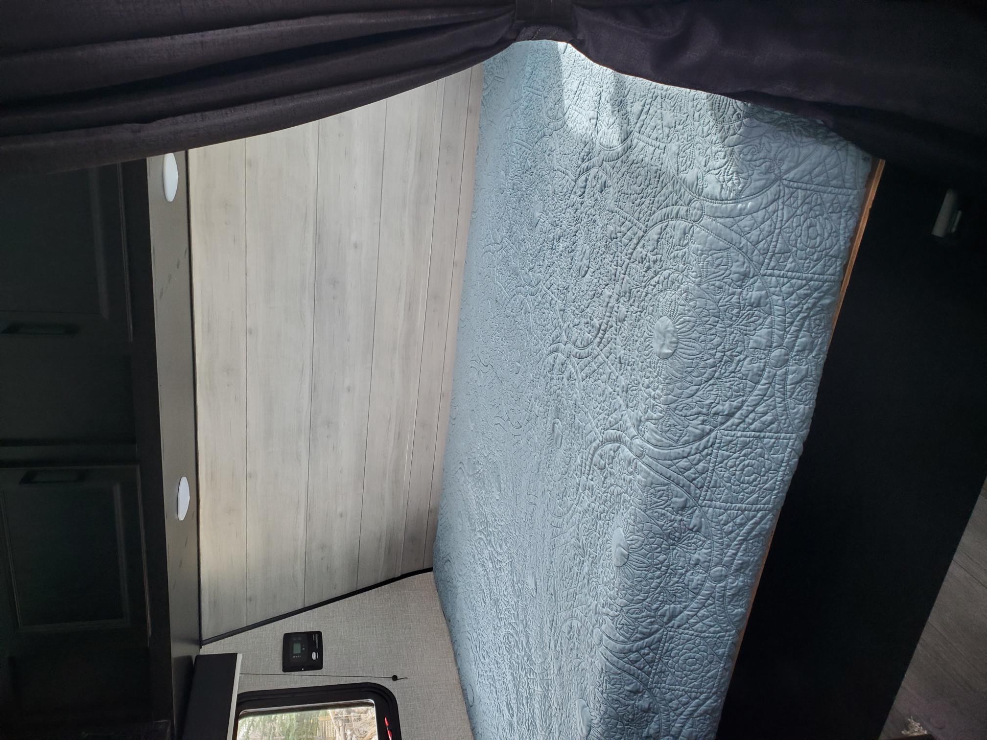 Cozy RV rental bedroom with a quilted bed, wood paneling, and controls.. Jayco Jay Flight SLX Baja 2022