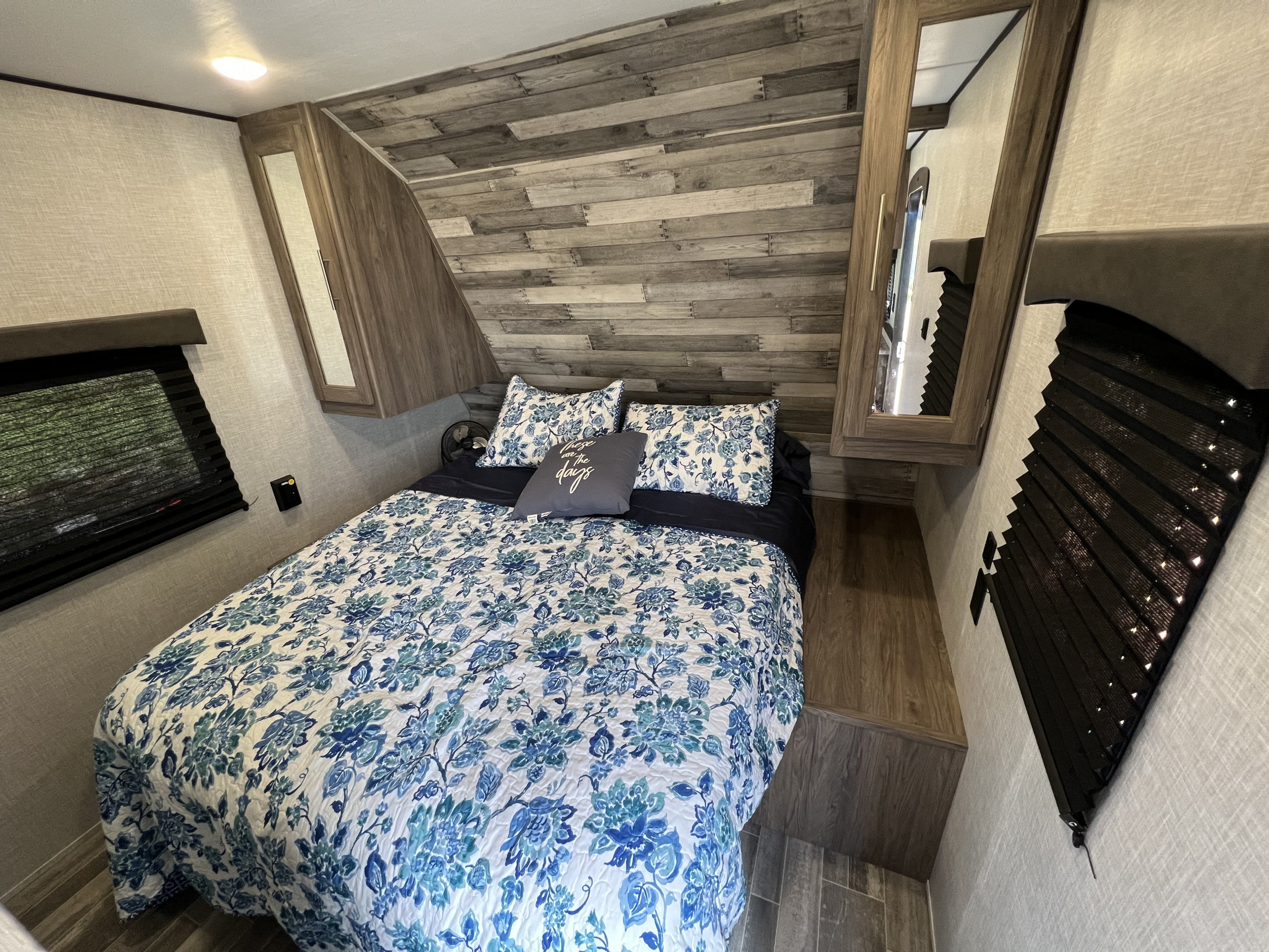 RV rental: A cozy bedroom with blue floral bedding, a wood plank accent wall, and convenient mirrored storage.. Crossroads 270BH 2022