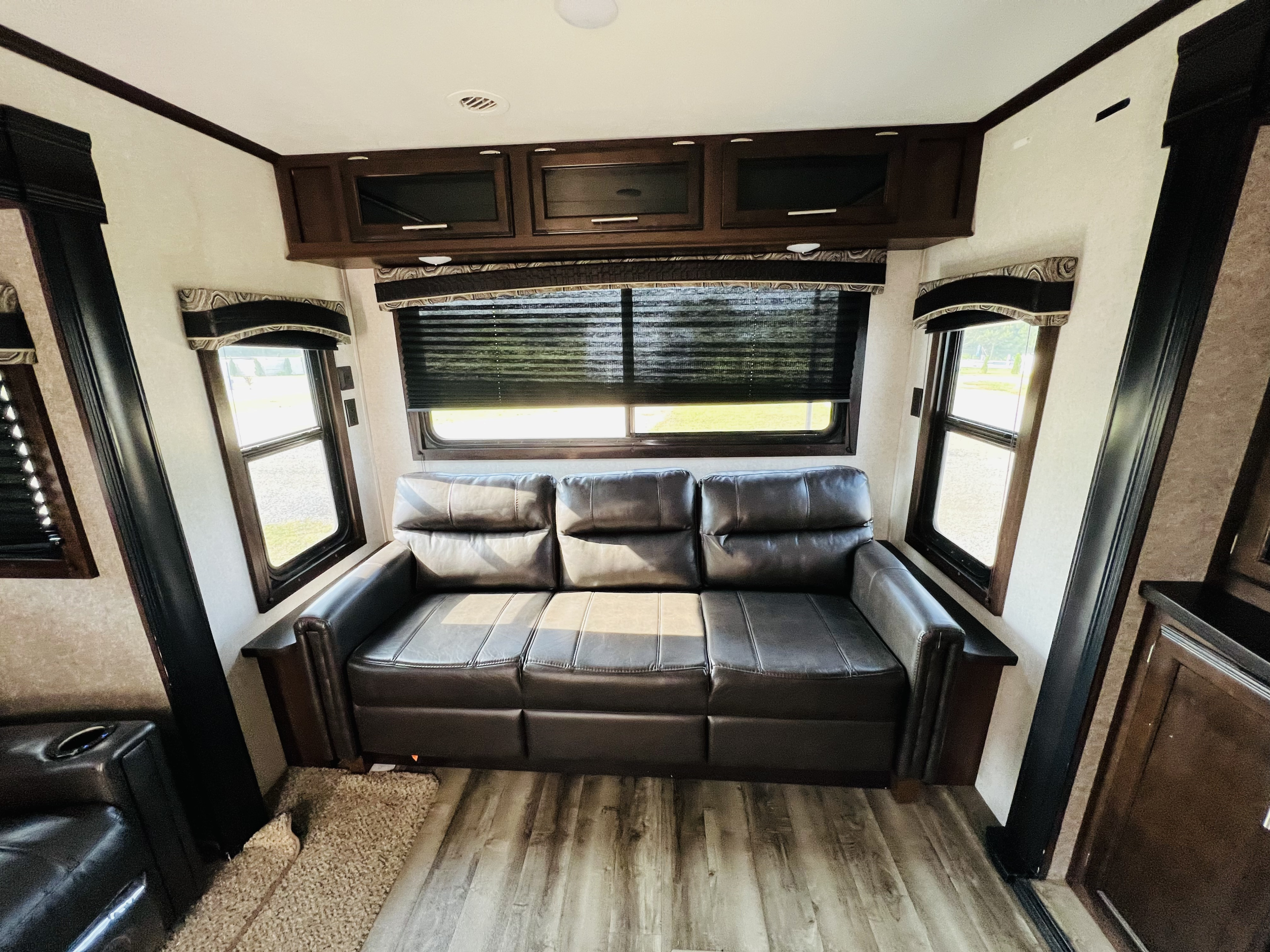 Spacious RV rental interior with a brown sofa, large windows with blinds, and overhead cabinetry. Ideal living space.. Jayco Jay Flight 2019