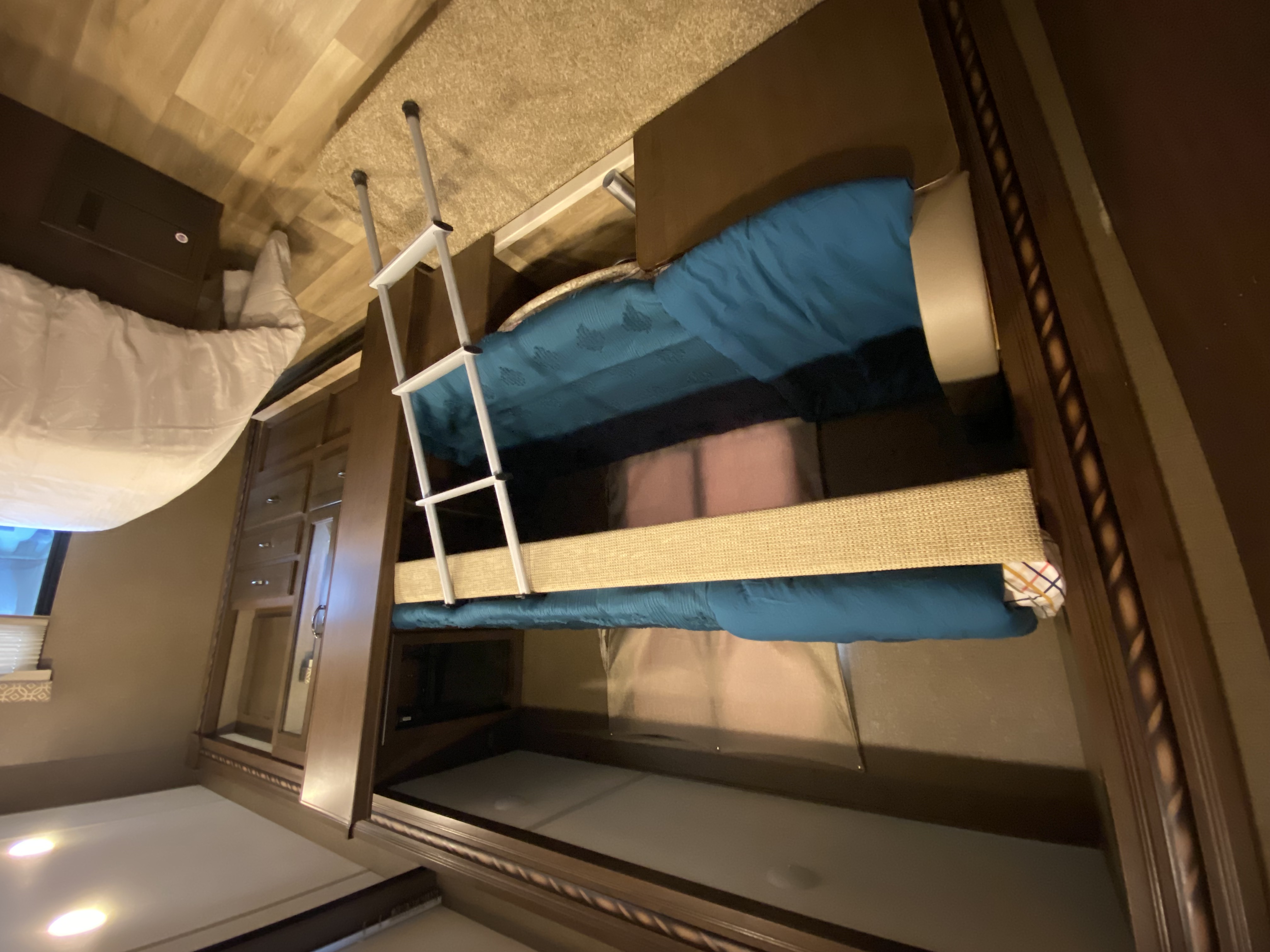 RV rental interior featuring bunk beds with a ladder. A blue comforter is on the upper bunk, providing compact sleeping.. Thor Freedom Elite 2018